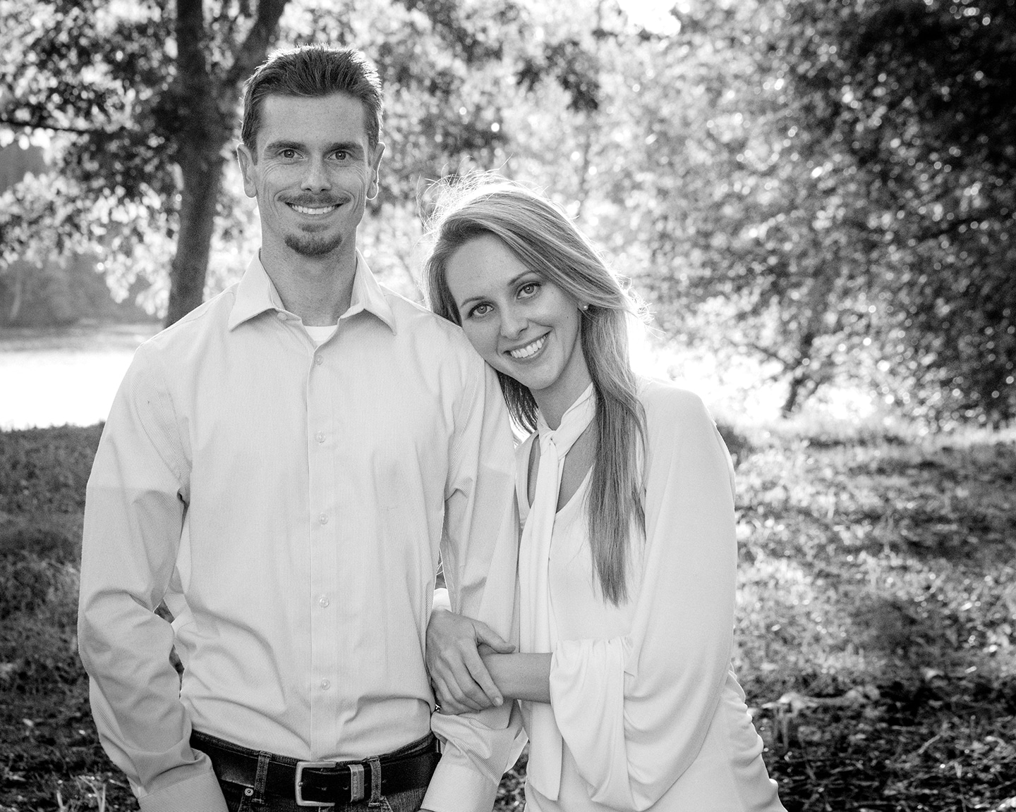 Tim and Shannon of DeLong Photography in a public park Black and white image of Tim and Shannon DeLong of DeLong Photography in Riverfront Park park smiling at the camera