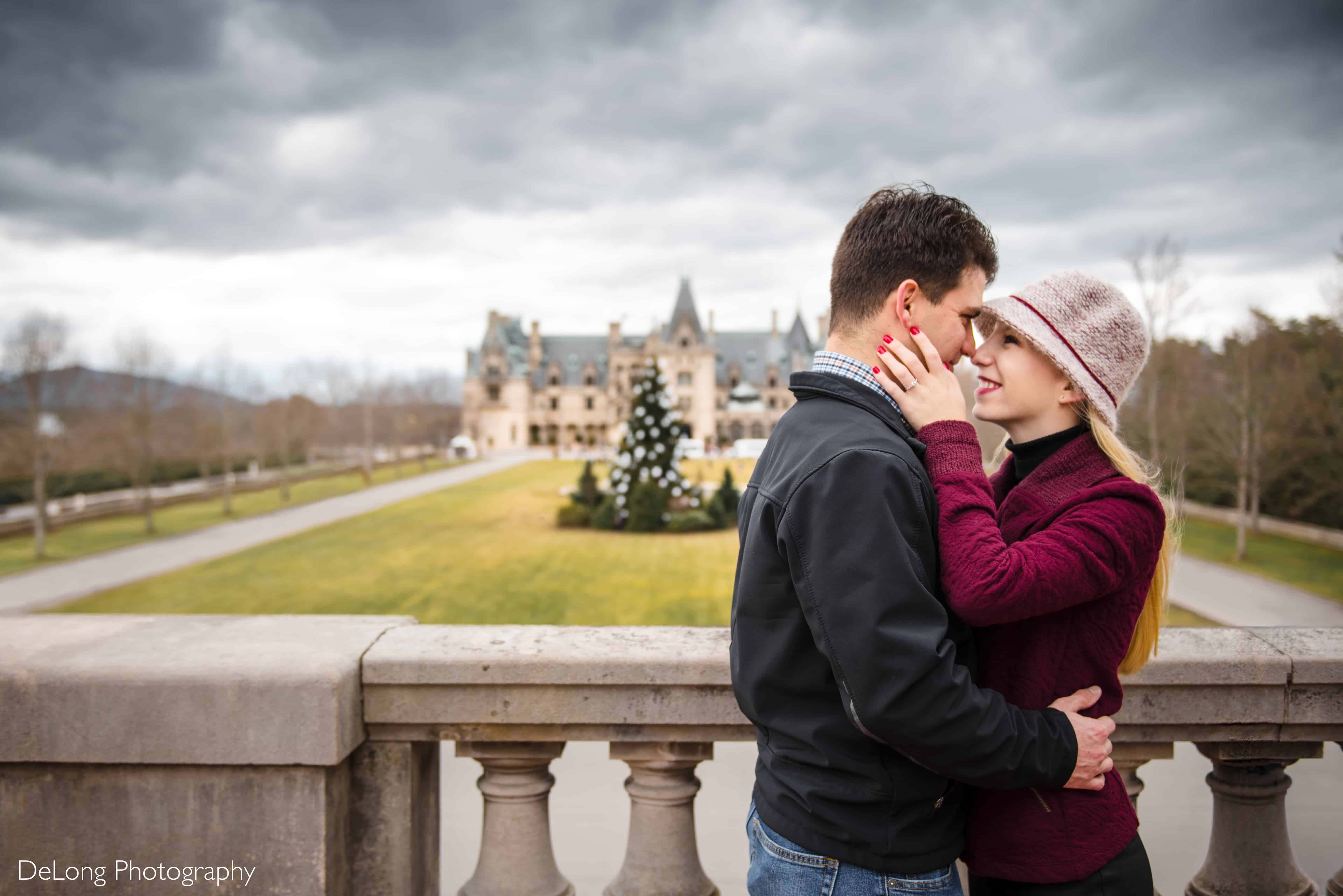 Engaged couple smiling, touching noses in front of the Biltmore estate