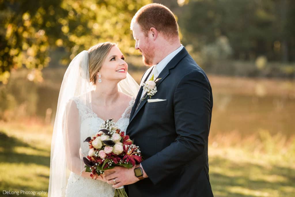 A couple looking into each others eyes outdoors by the pond during sunset at The Farmstead by Charlotte Wedding Photographers DeLong Photography