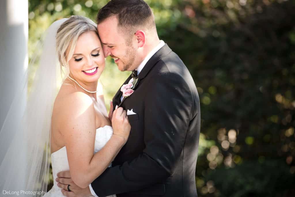 Portrait of Groom nuzzling into bride's temple smiling outdoors at The Magnolia Room by Charlotte Wedding Photographers DeLong Photography