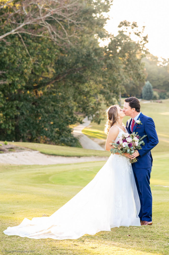 Bride and groom kissing on the golf course at Pine Island Country Club during golden hour by Charlotte wedding photographers DeLong Photography