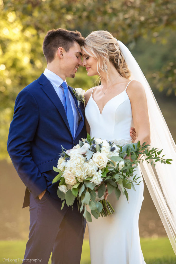 Portrait of bride and groom nuzzling foreheads together at the lakefront location at River Creek Lodge in Hiddenite, NC by Charlotte Wedding Photographers DeLong Photography