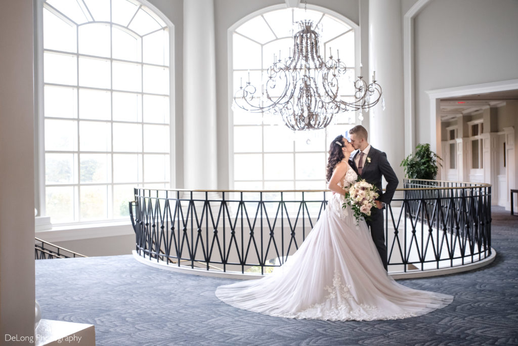 Bride and groom kissing under the Ballantyne hotel crystal chandelier by Charlotte Wedding Photographers DeLong Photography