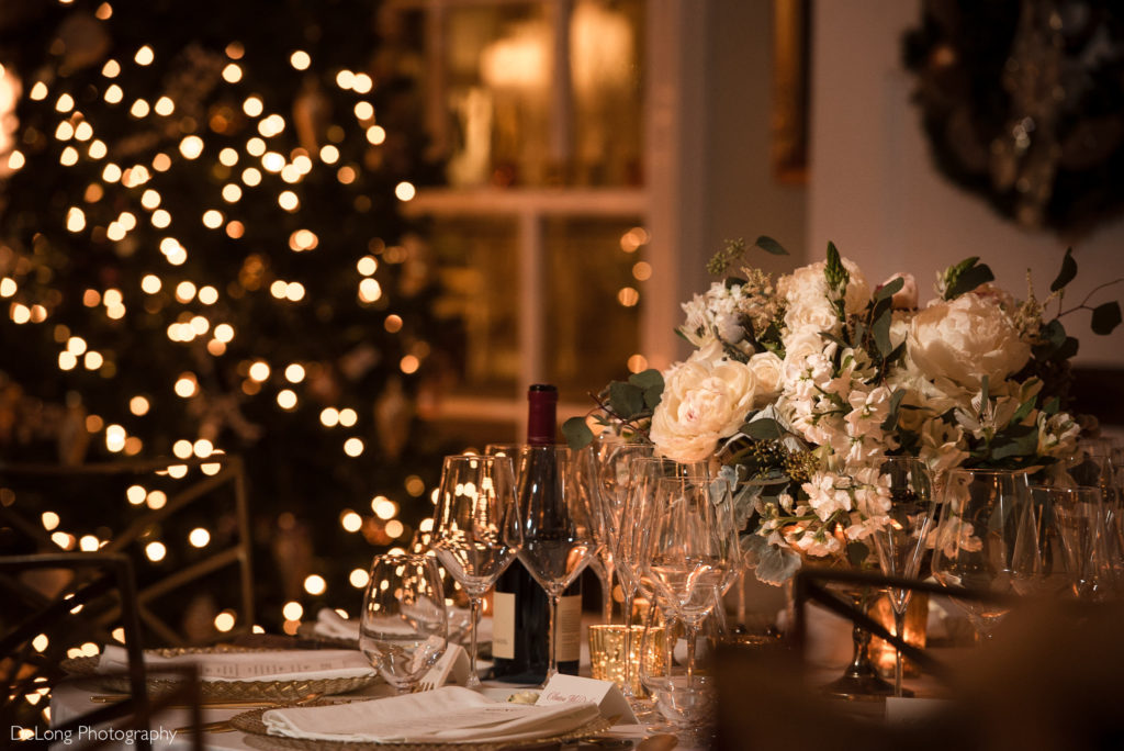 Detail photograph of a low floral arrangement on table surrounded by twinkling lights and glassware at The Morehead Inn by Charlotte Wedding Photographers DeLong Photography