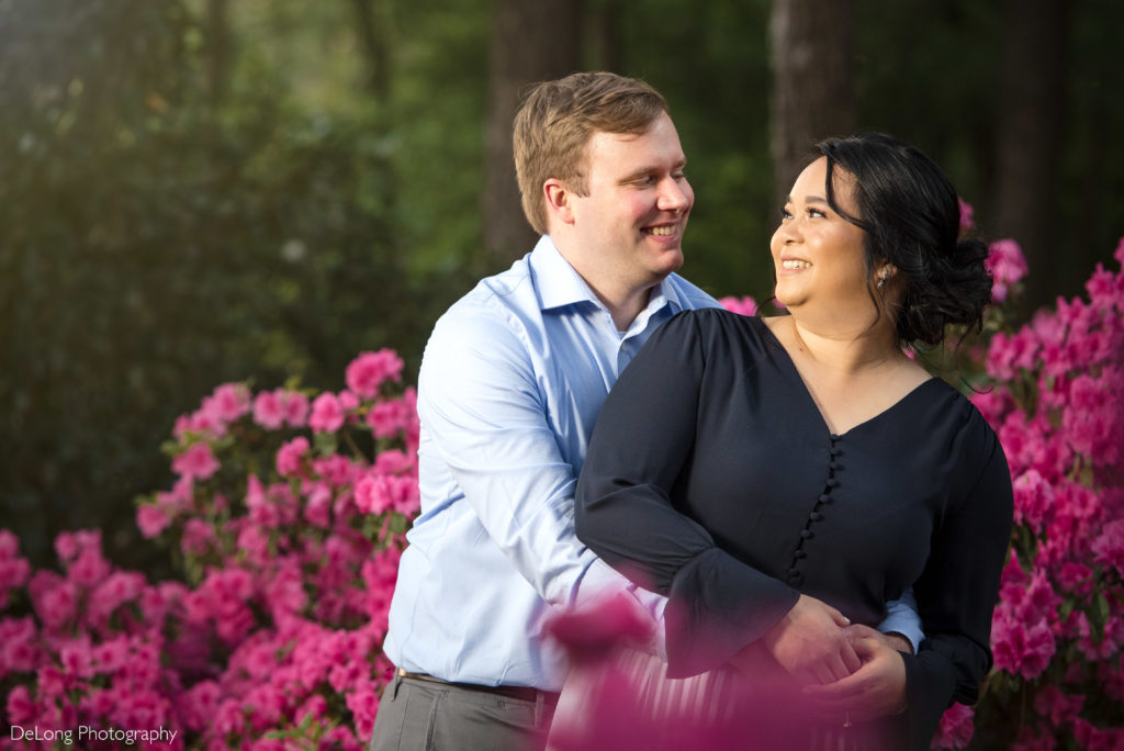 Couple smiling at each other in front of floral backdrop at Jetton Park