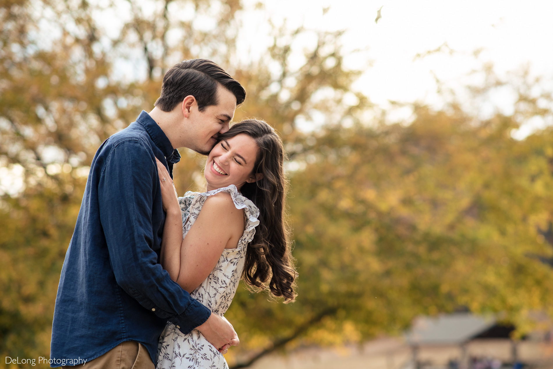 Giggling engaged couple portrait outside at a Freedom park in Charlotte, NC by Charlotte Wedding Photographers DeLong Photography