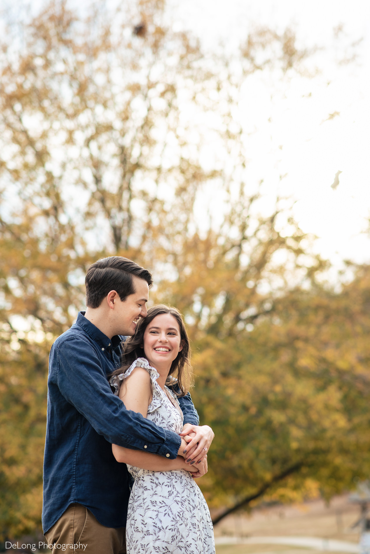 Giggling engaged couple portrait outside at a Freedom park in Charlotte, NC by Charlotte Wedding Photographers DeLong Photography