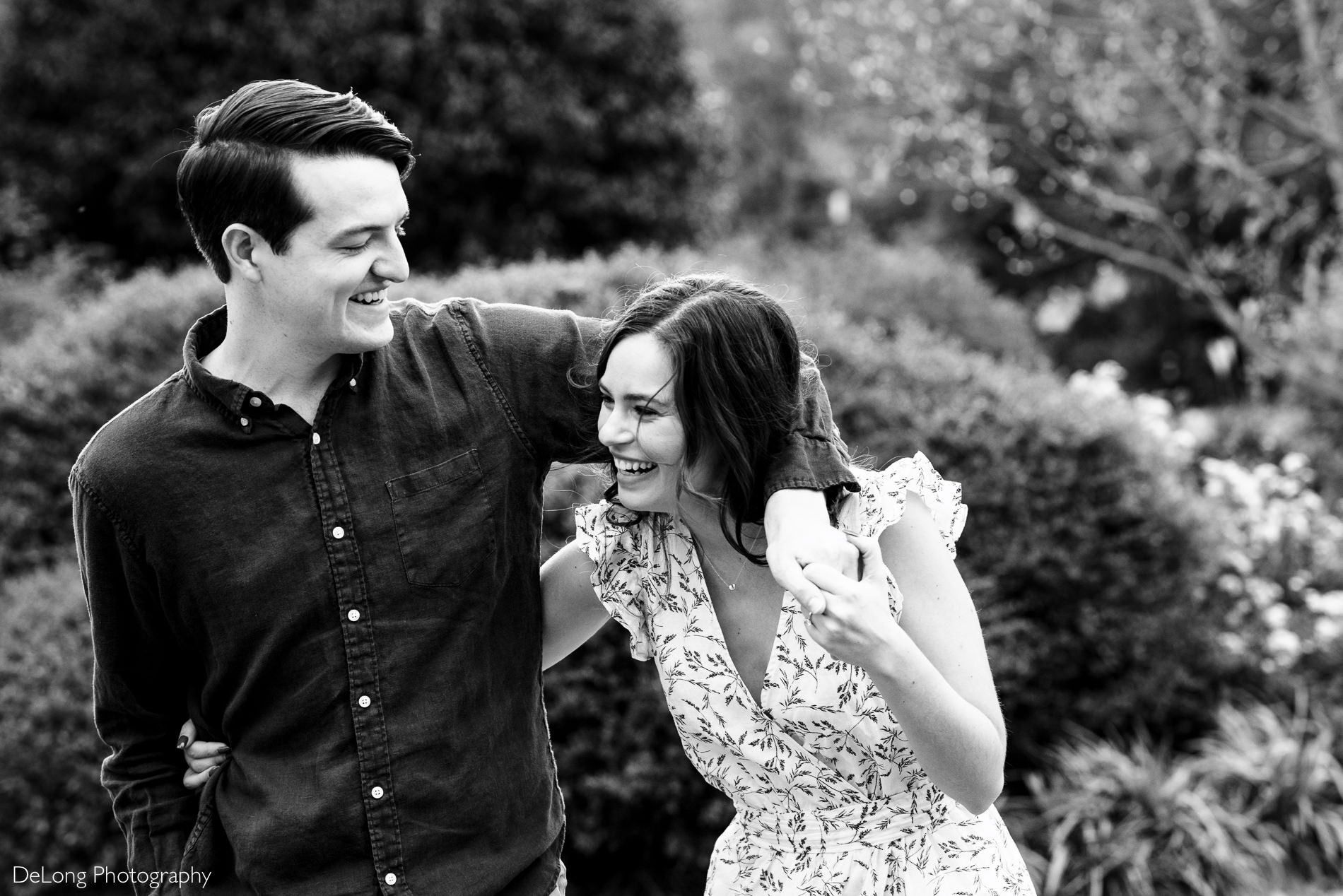 Man with his arm around his fiancee laughing at a Freedom park in Charlotte, NC by Charlotte Wedding Photographers DeLong Photography