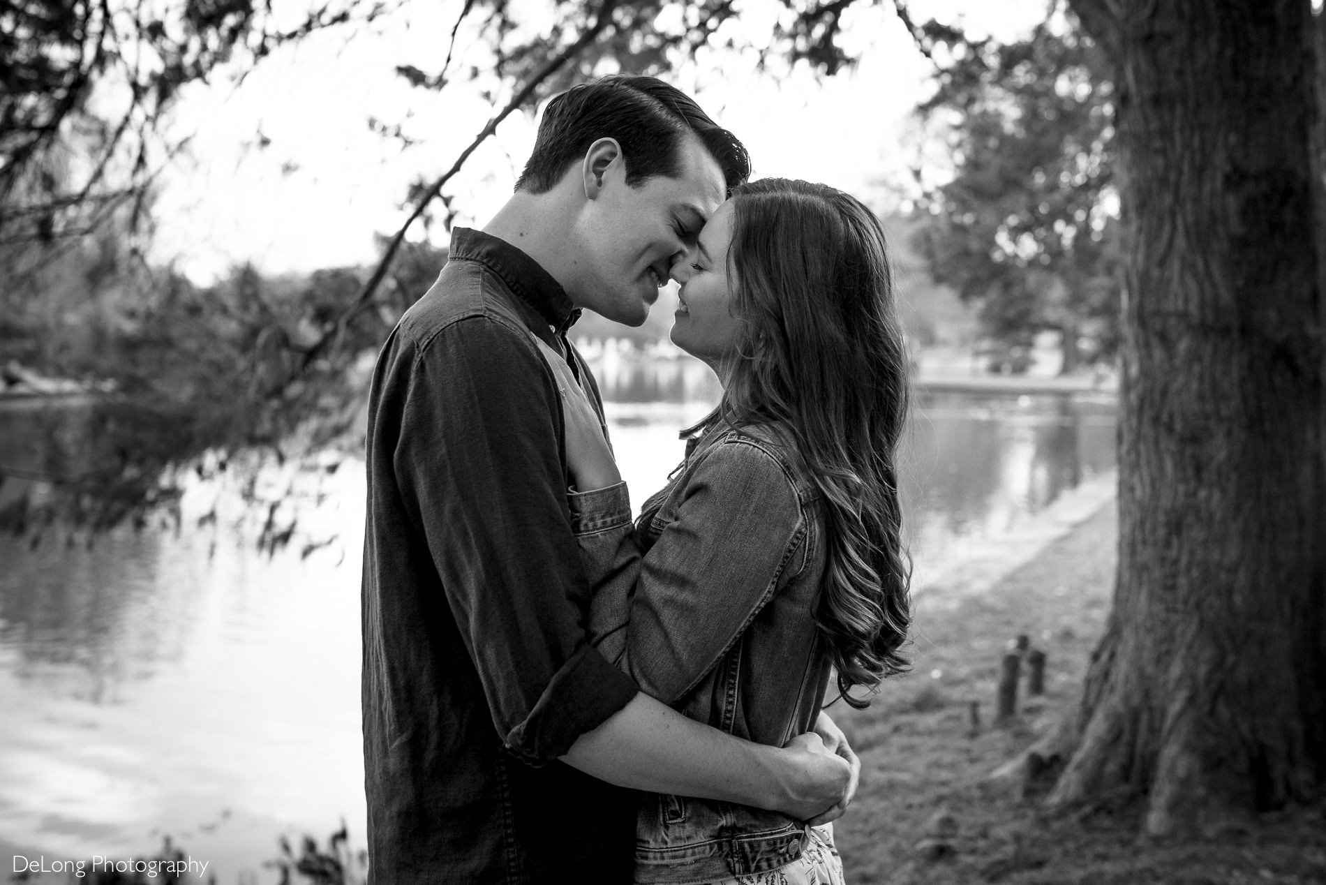 Engaged couple smiling just before a kiss outside near the pond at Freedom Park by Charlotte wedding photographers DeLong Photography