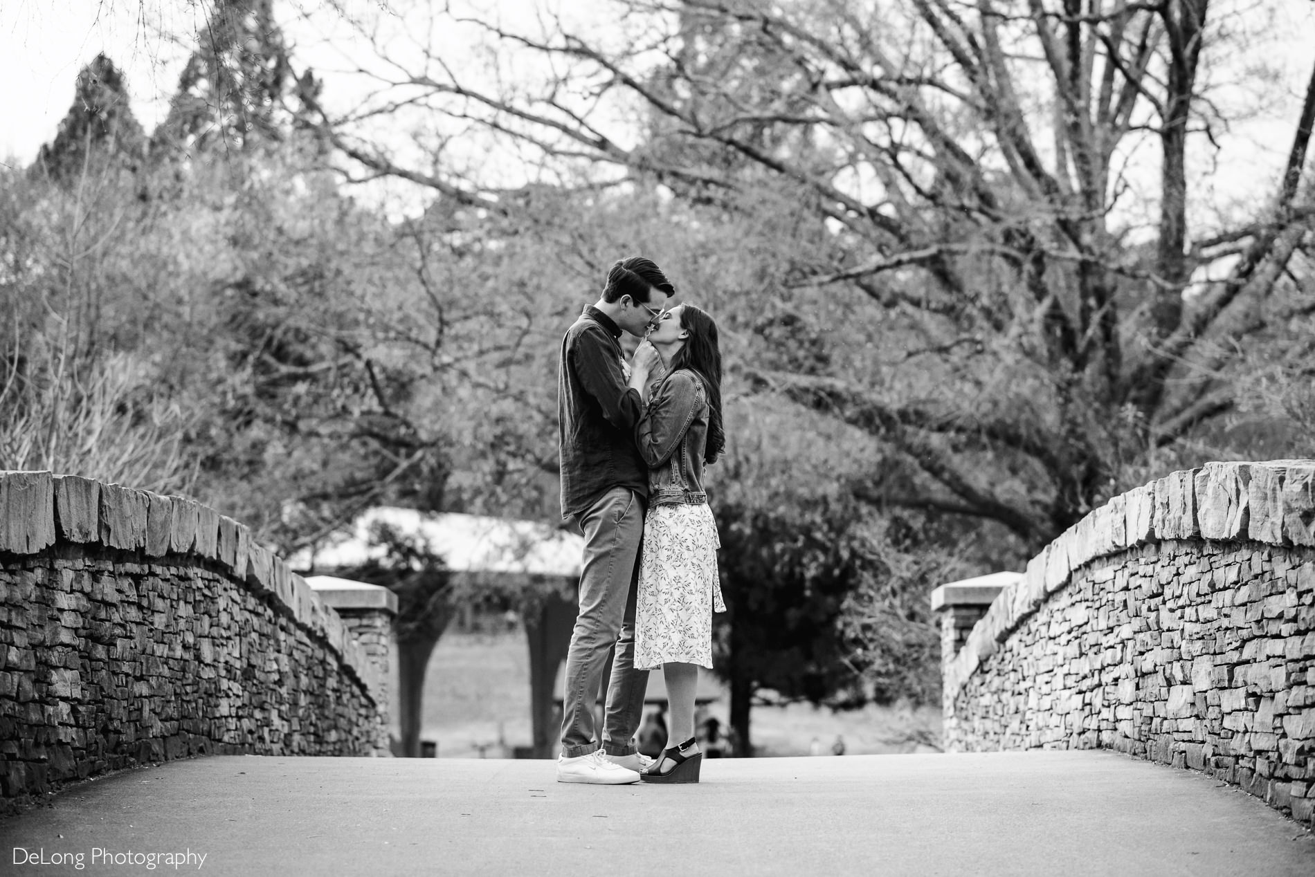 Black and white image of couple about to kiss standing on the bridge at Freedom Park by Charlotte wedding photographers DeLong Photography