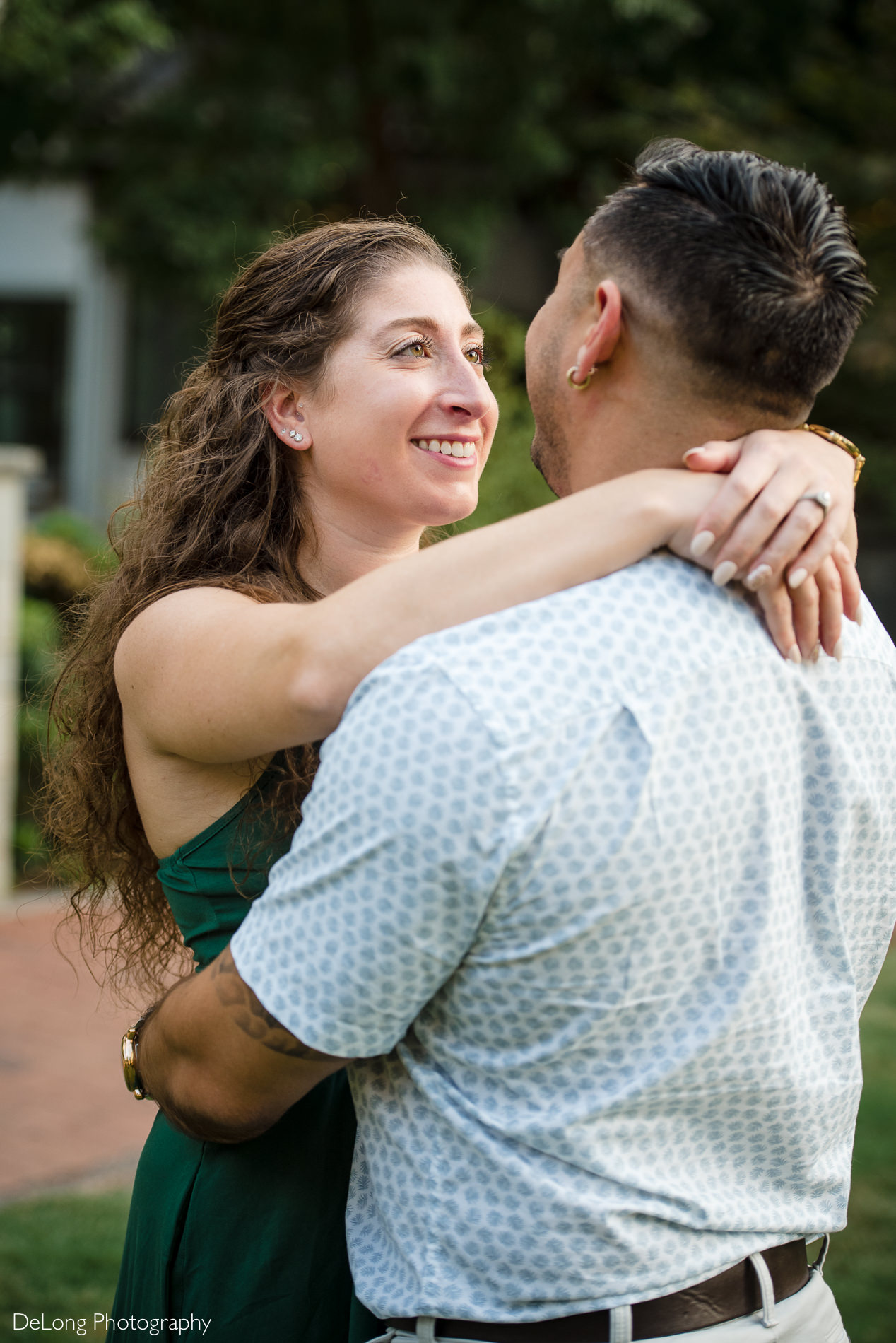 Woman looking at man lovingly with arms wrapped around his shoulders in Romare Bearden Park by Charlotte wedding photographers DeLong Photography