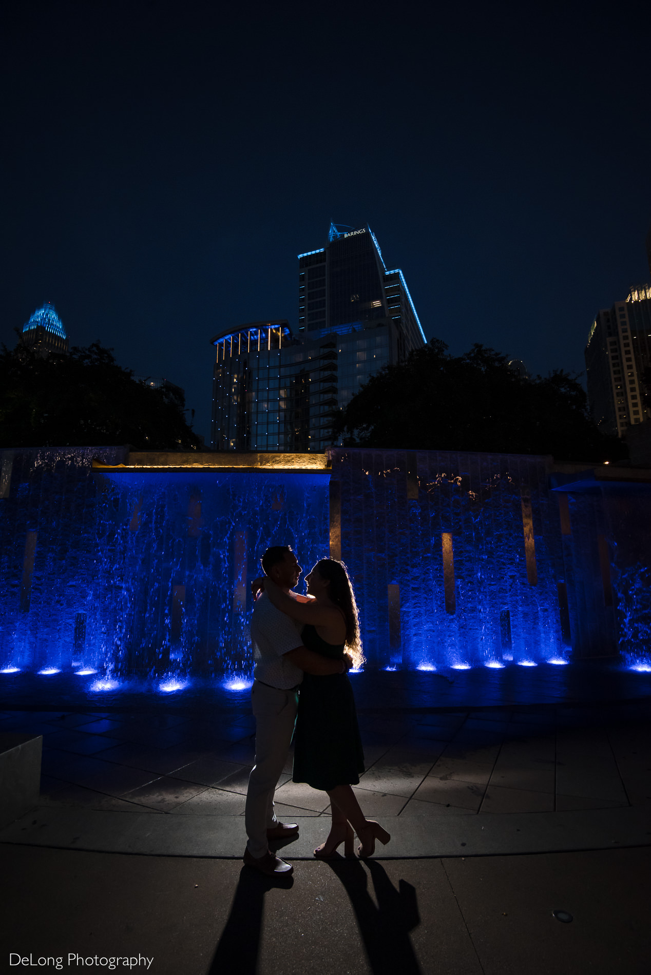 Couple silhouetted against a water fountain during a Romare Bearden Park engagement session by Charlotte wedding photographers DeLong Photography