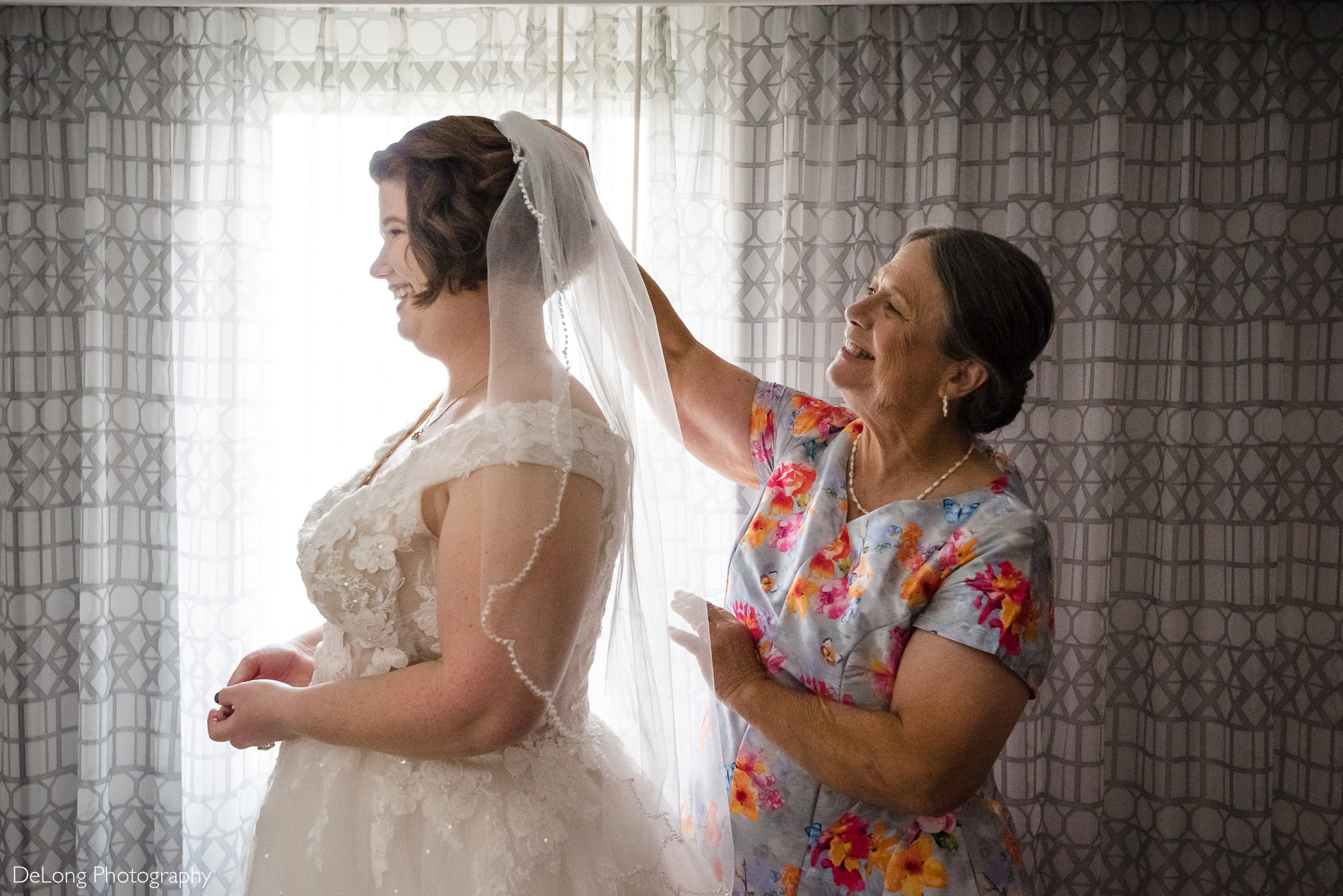 Bride's mother putting in bride's veil by Charlotte wedding photographers DeLong Photography