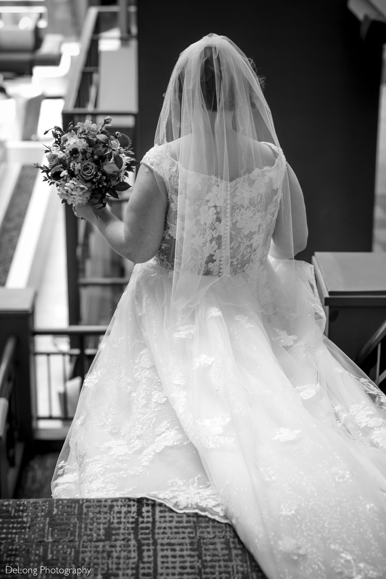 Bride descending stairs at Embassy Suites by Hilton Charlotte by Charlotte wedding photographers DeLong Photography