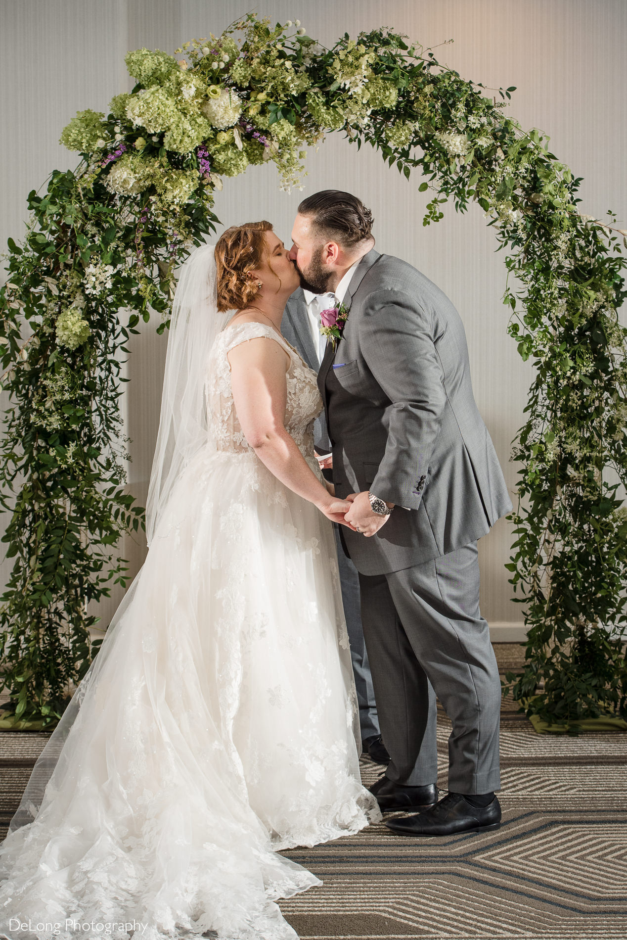 Bride and groom first kiss during wedding ceremony by Charlotte wedding photographers DeLong Photography