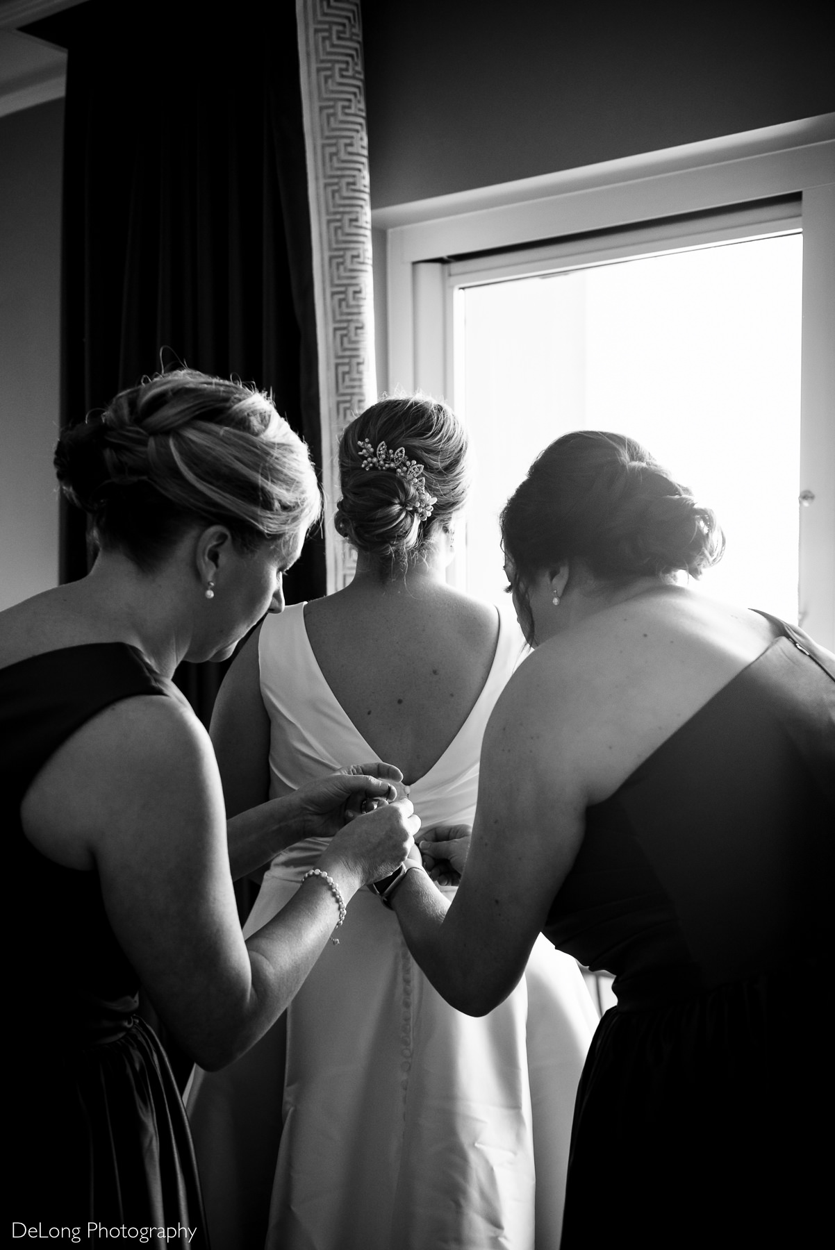 Matrons of Honor buttoning up the bride's dress by Charlotte Wedding Photographers DeLong Photography