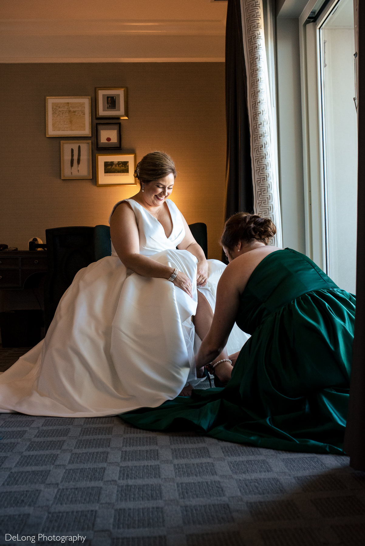 Matron of Honor helps put on bride's shoes at the Ballantyne Hotel by Charlotte Wedding Photographers DeLong Photography