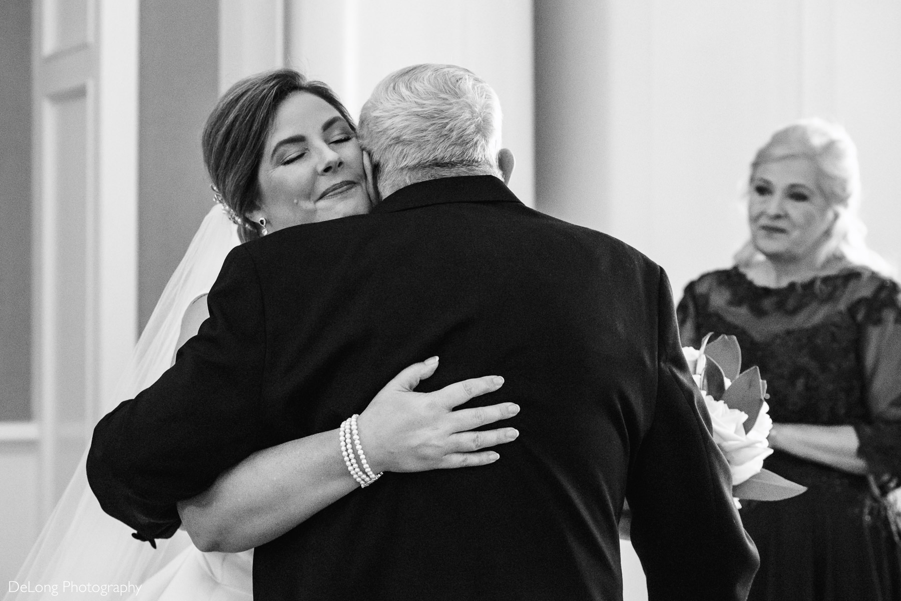 Father and daughter hugging during first look while the bride's mother looks on smiling by Charlotte Wedding Photographers DeLong Photography
