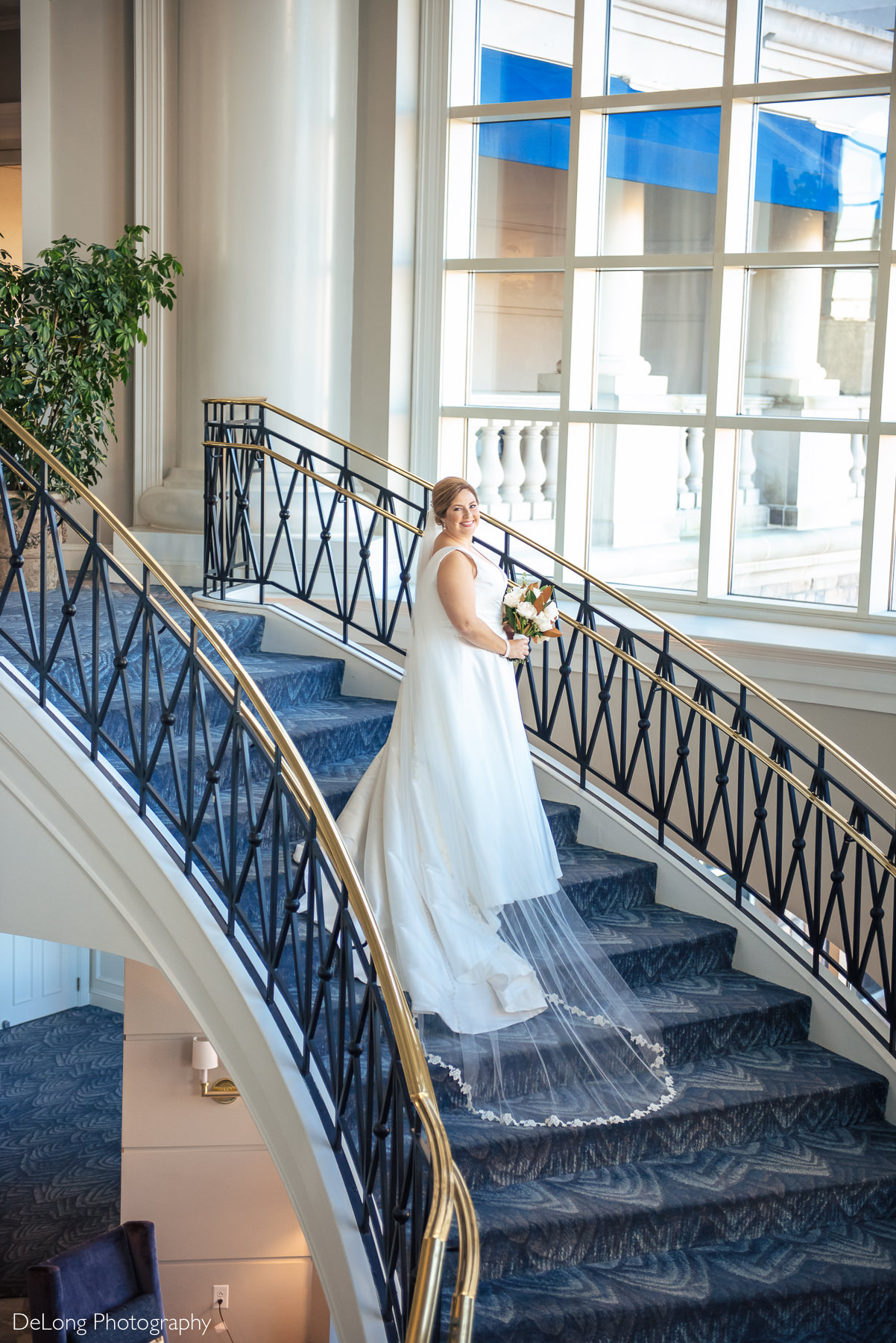 Bridal portrait with her veil and trail cascading down the staircase at the Ballantyne Hotel by Charlotte Wedding Photographers DeLong Photography