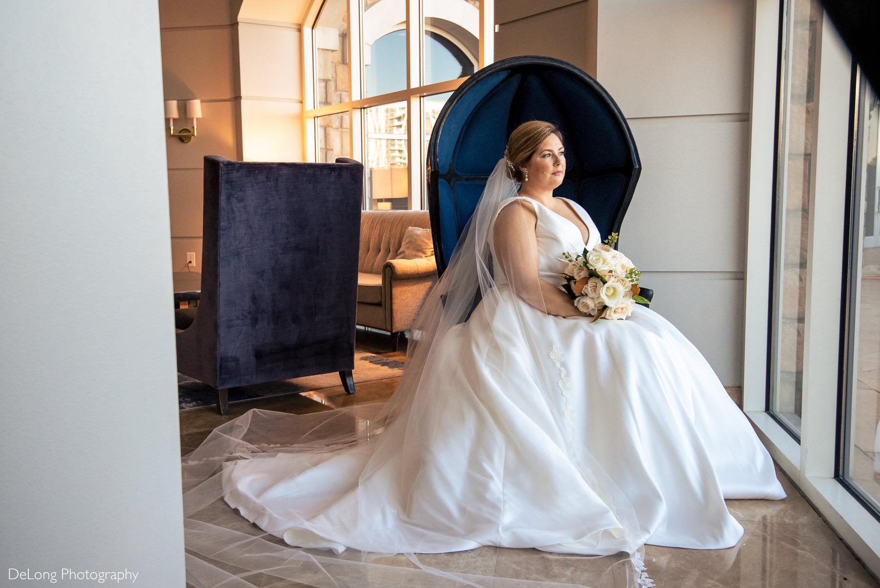 Seated bridal portrait in large blue egg chair at the Ballantyne Hotel by Charlotte Wedding Photographers DeLong Photography