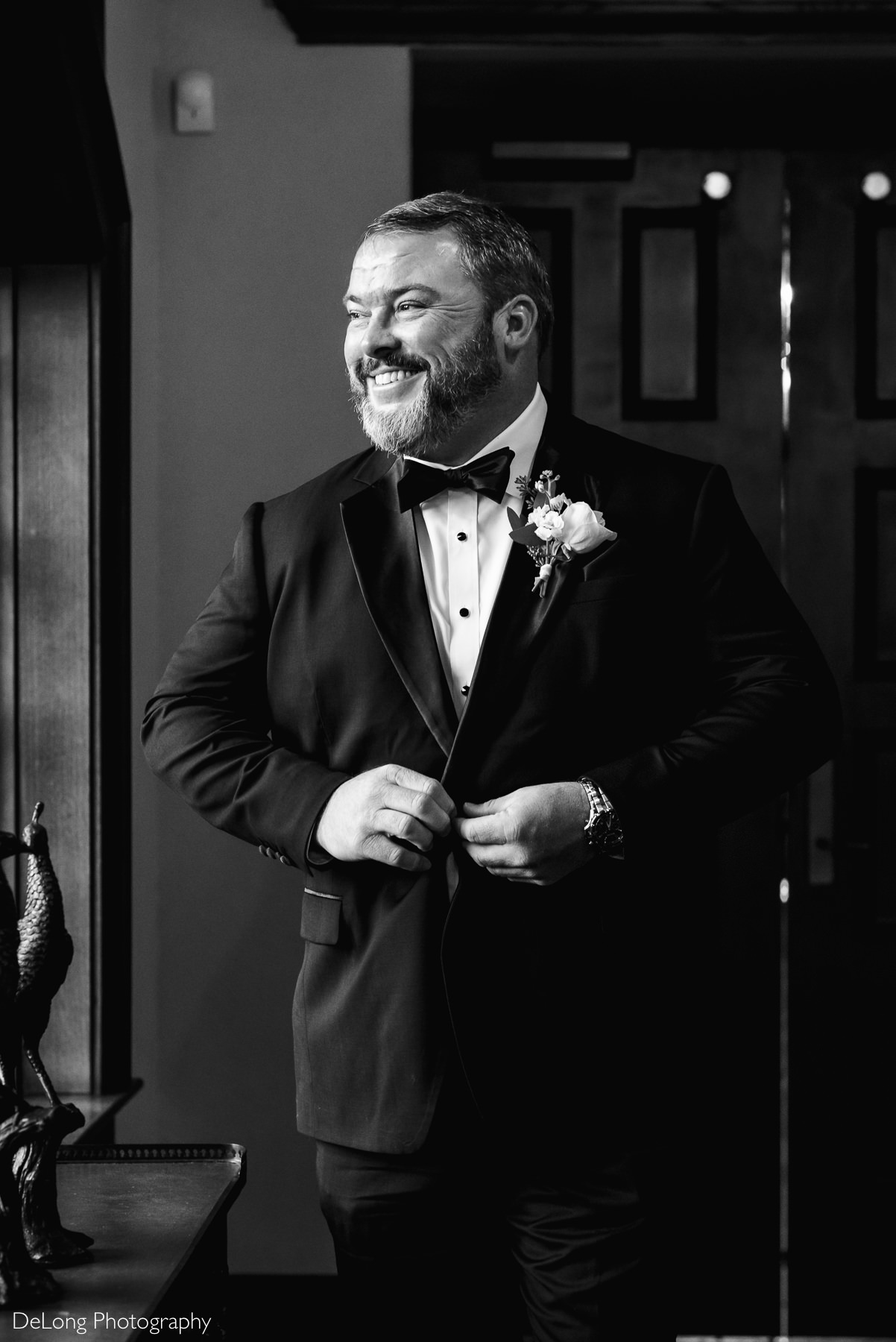Indoor groom portrait as he buttons his jacket by Charlotte Wedding Photographers DeLong Photography
