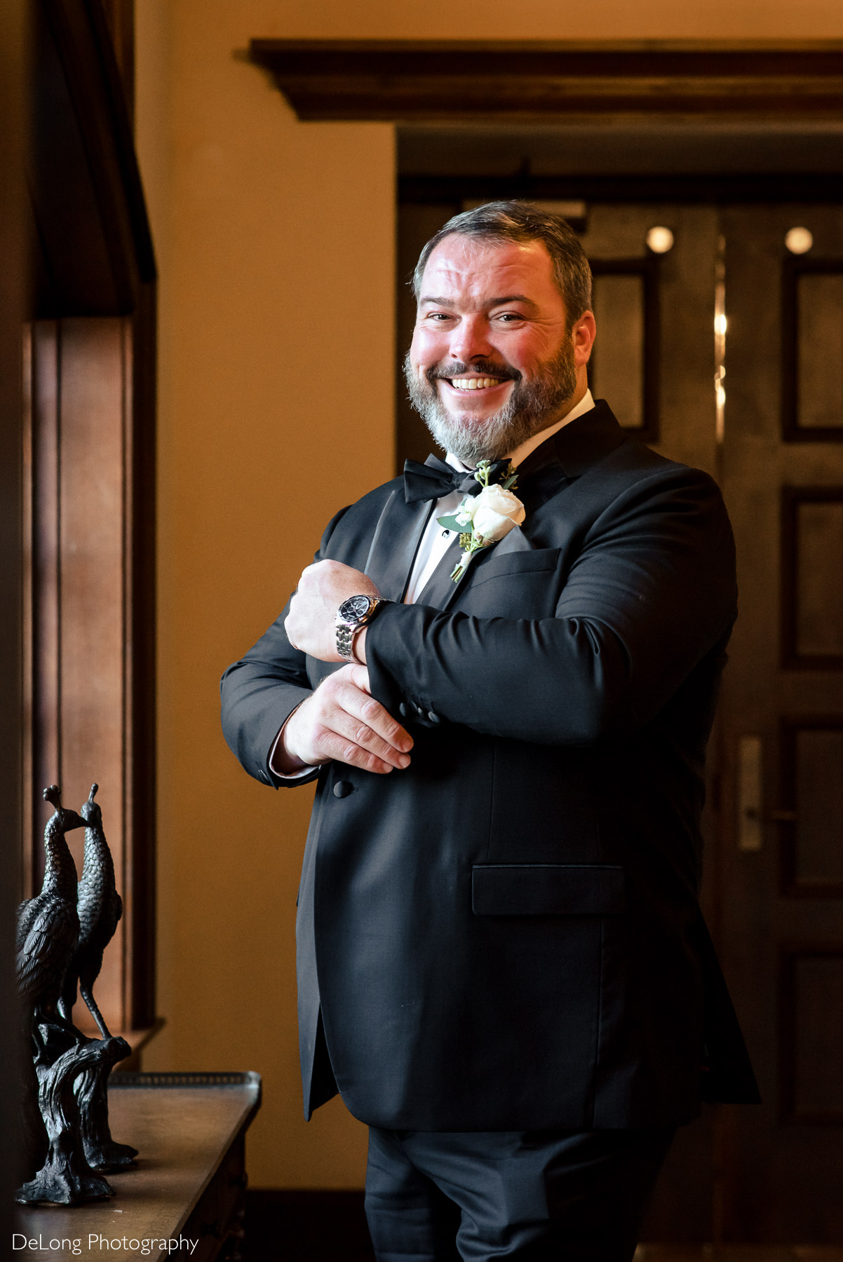 Indoor groom portrait of him while he adjusts his sleeve by Charlotte Wedding Photographers DeLong Photography