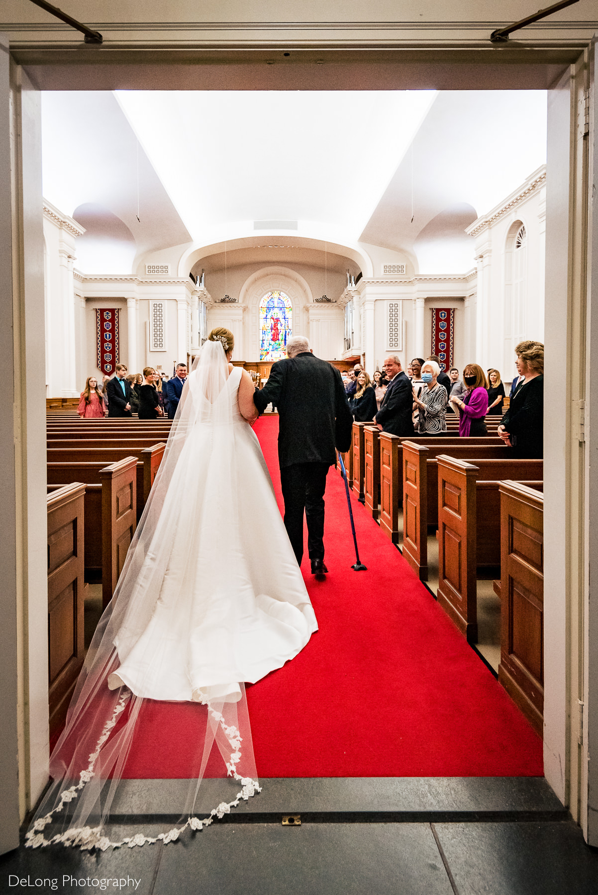 Bride being escorted down the Providence Methodist Church aisle by Charlotte Wedding Photographers DeLong Photography