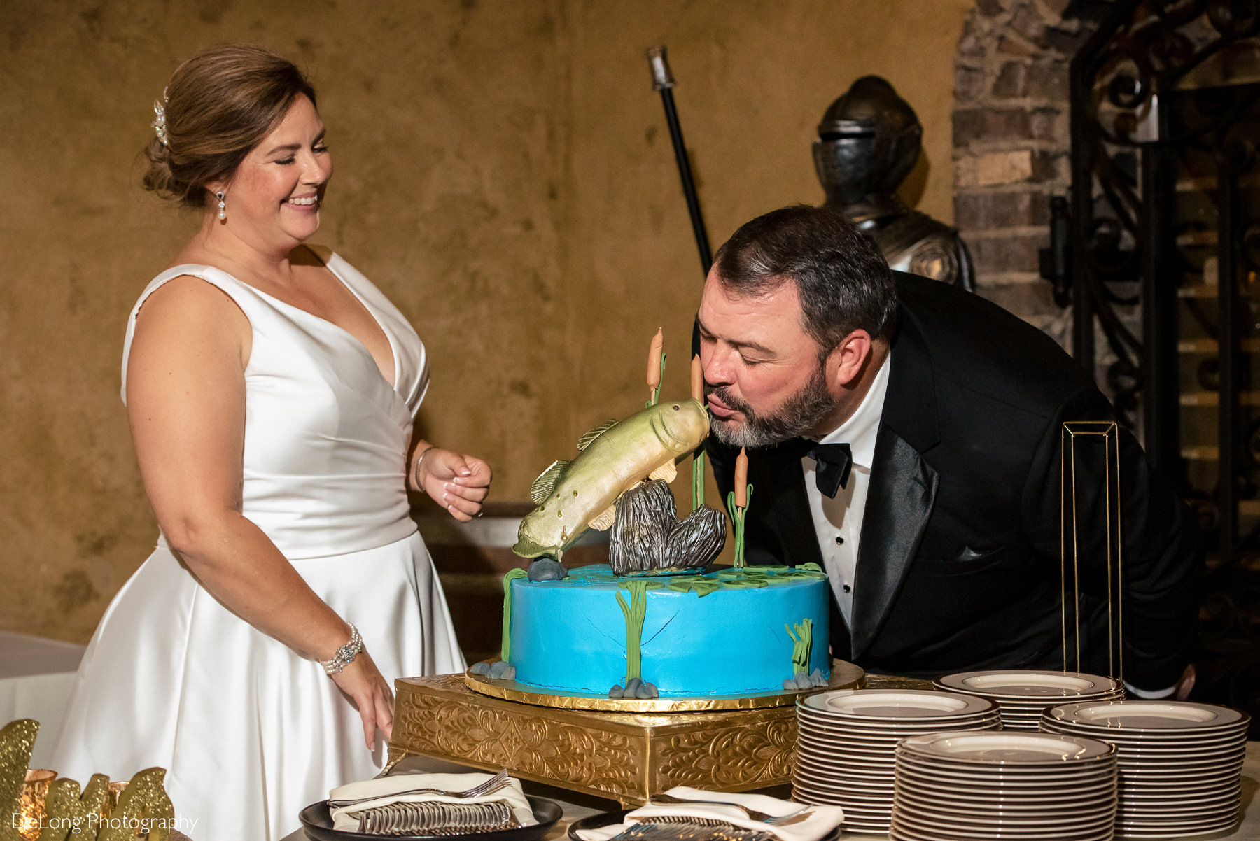 Groom kissing the fish of his groom's cake making bride laugh at The Club at Longview wedding by Charlotte Wedding Photographers DeLong Photography