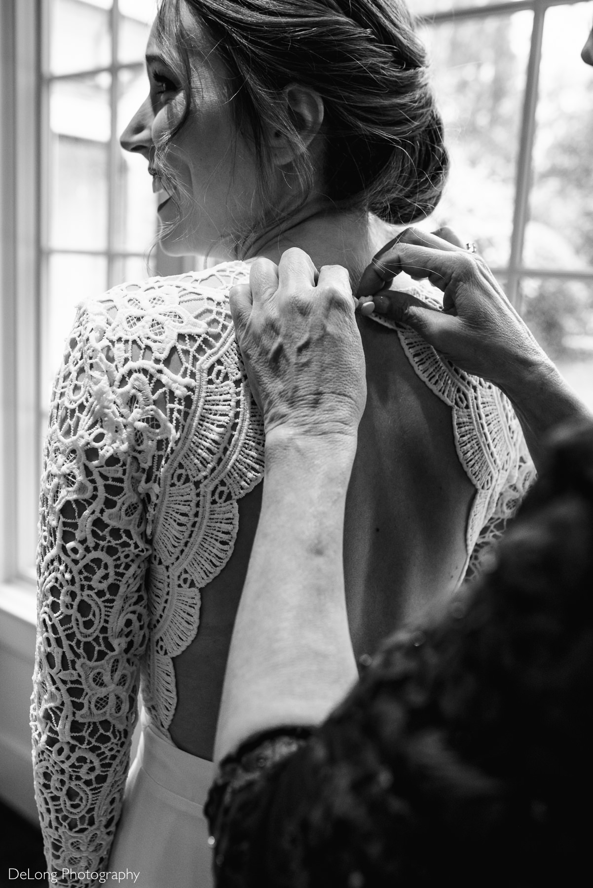 Black and white image from behind the bride of her mother buttoning the top of her Lulus wedding dress by Charlotte wedding photographers DeLong Photography