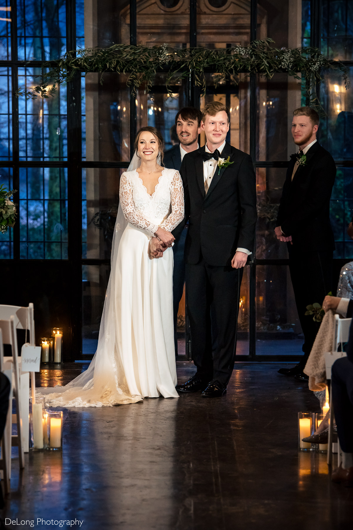 Bride and groom holding hands smiling out at their guests during their wedding ceremony at the Westside warehouse in Atlanta by Charlotte wedding photographers DeLong Photography