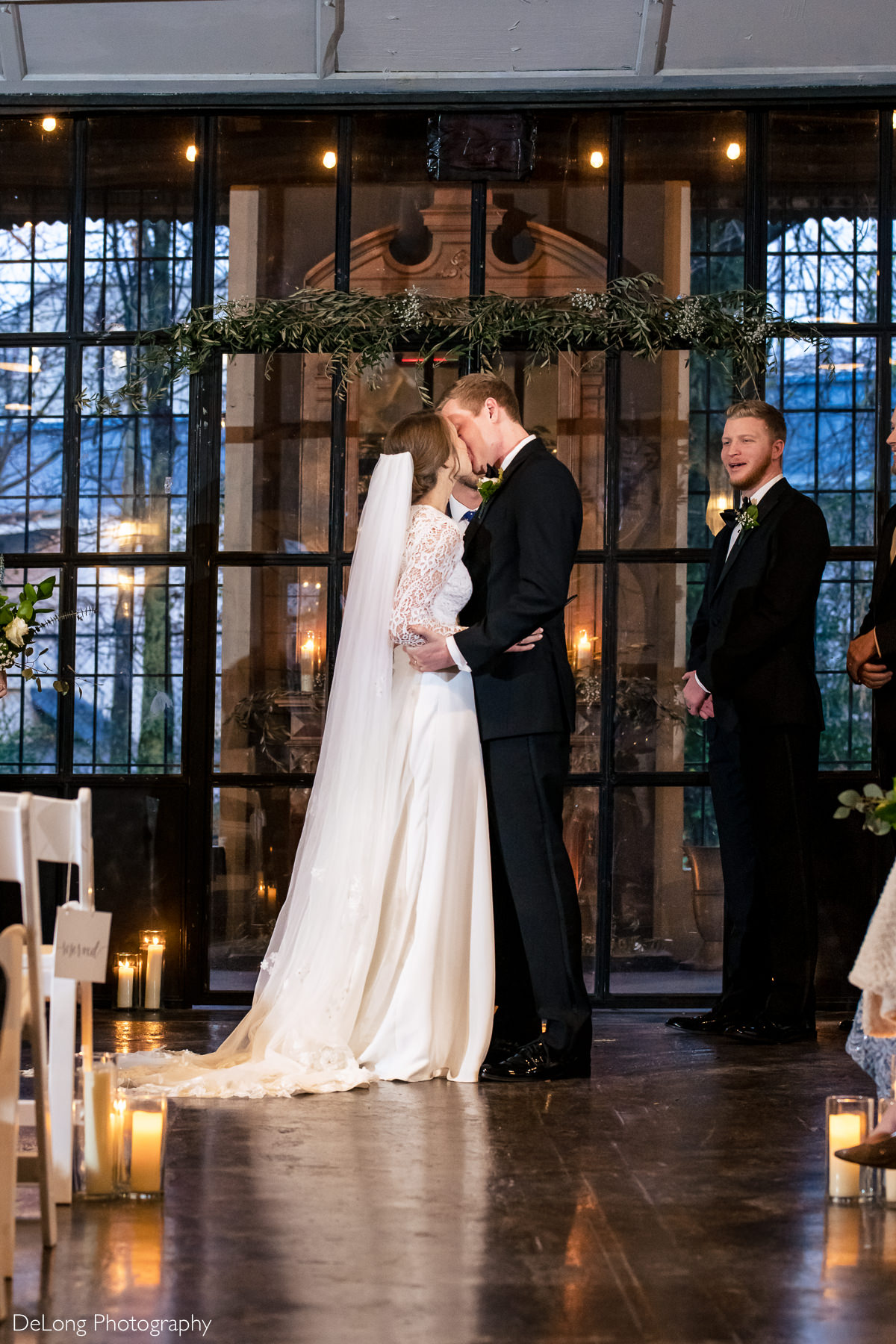 Bride and groom's first kiss in front of the glass doors at the Westside warehouse in Atlanta by Charlotte wedding photographers DeLong Photography