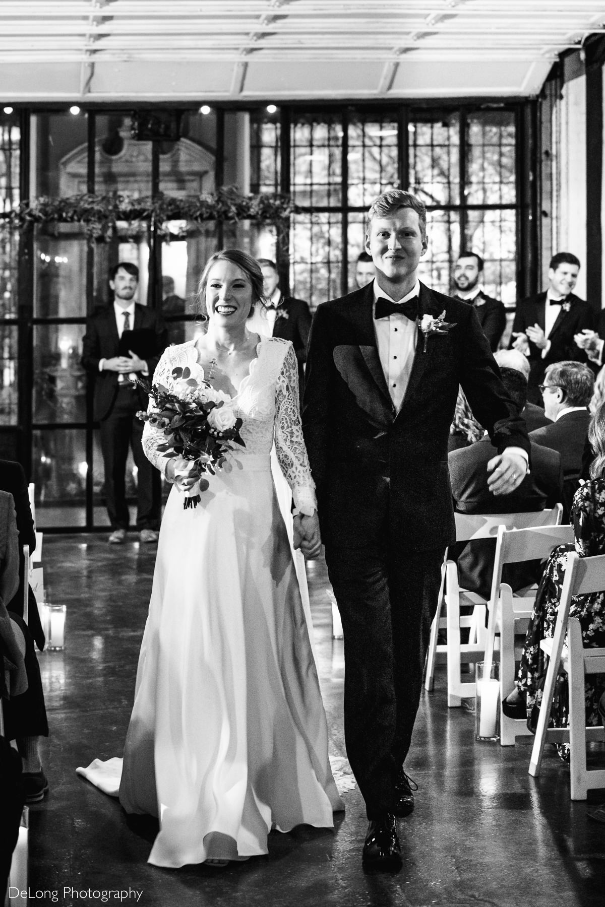Black and white image of a bride and groom receding down the aisle smiling at the Westside warehouse in Atlanta by Charlotte wedding photographers DeLong Photography