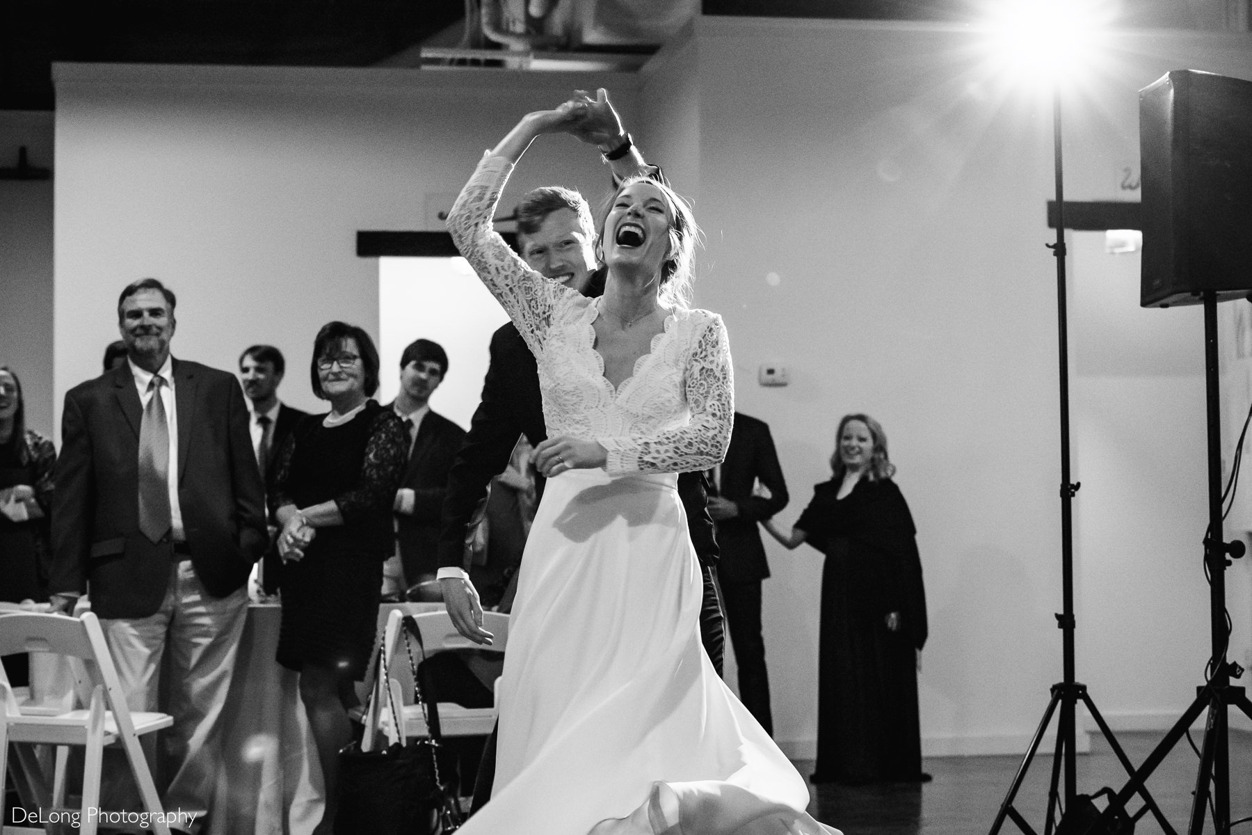 Black and white image of a bride cracking up laughing mid-spin during her first dance with her groom at the Westside warehouse in Atlanta by Charlotte wedding photographers DeLong Photography