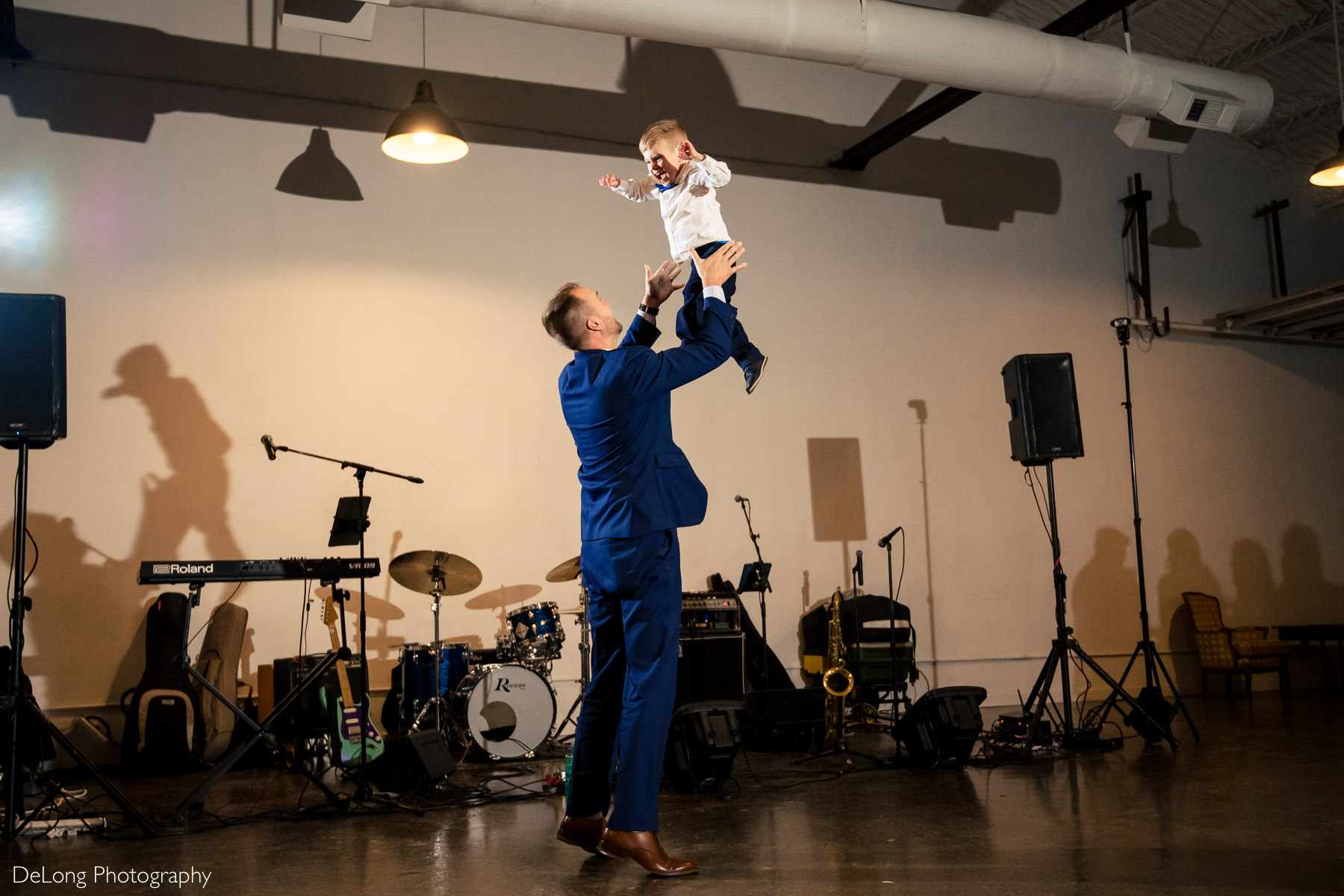 Photograph of a child laughing mid-air as he is being tossed upward during the reception at the Westside warehouse in Atlanta by Charlotte wedding photographers DeLong Photography