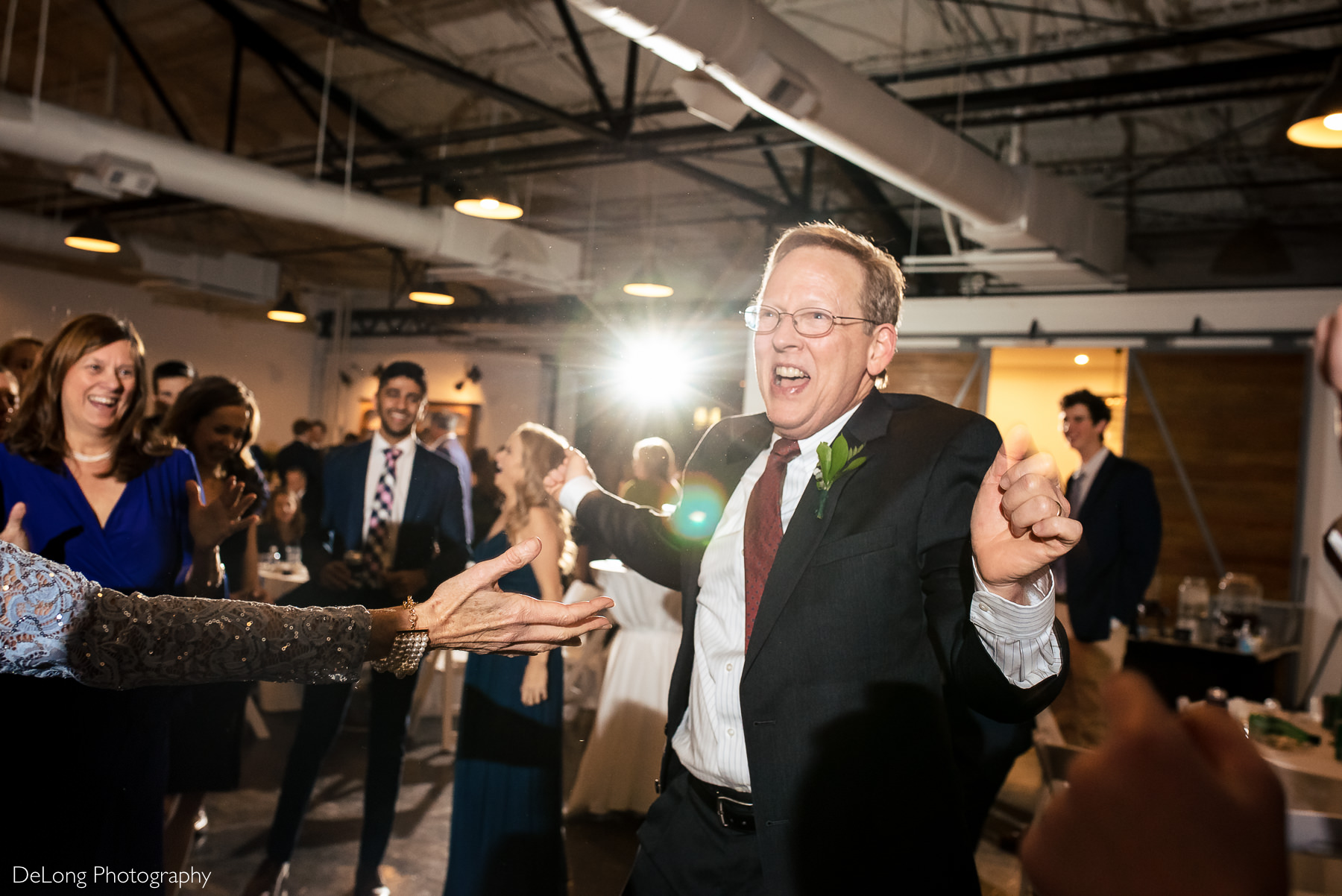 Father of the groom smiling making a fun dance expression during the reception dancing at the Westside warehouse in Atlanta by Charlotte wedding photographers DeLong Photography