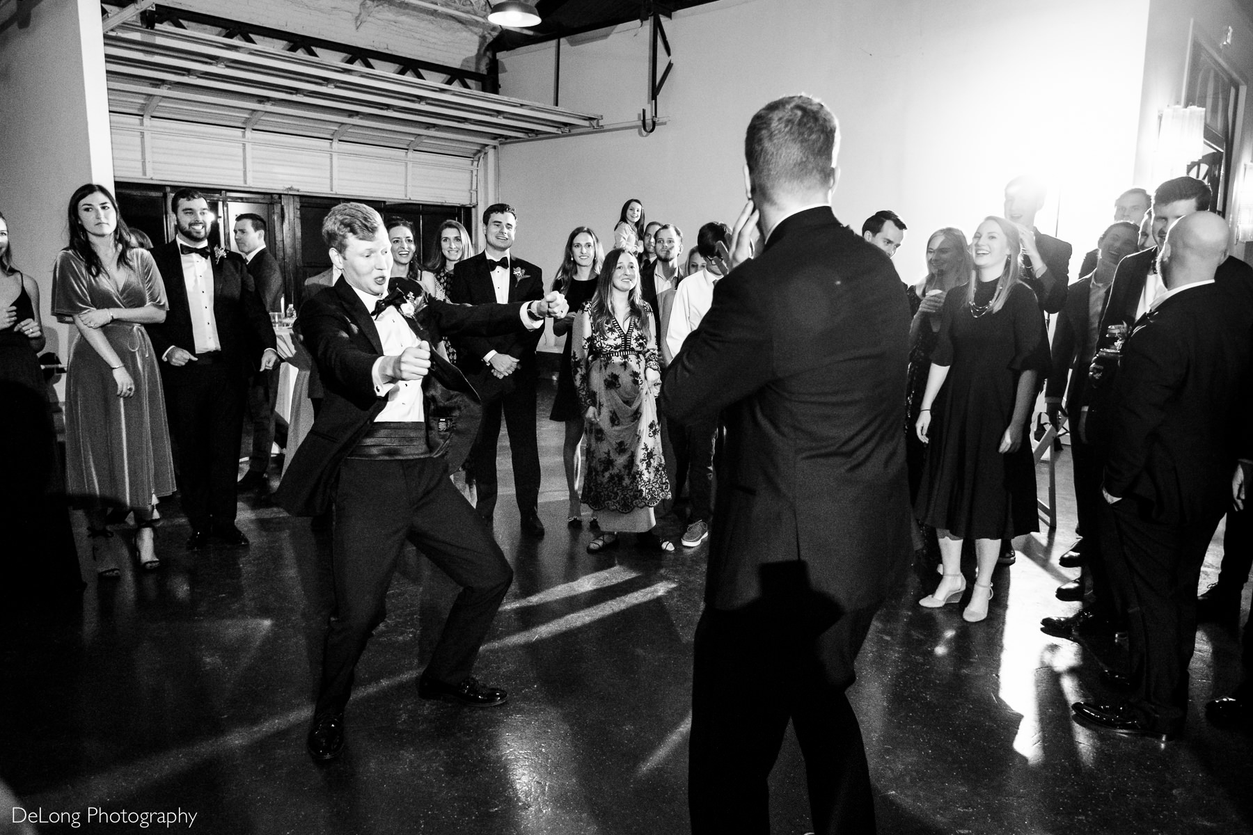 Black and white image of the groom breaking it down during a dance battle with his brother at the Westside warehouse in Atlanta by Charlotte wedding photographers DeLong Photography