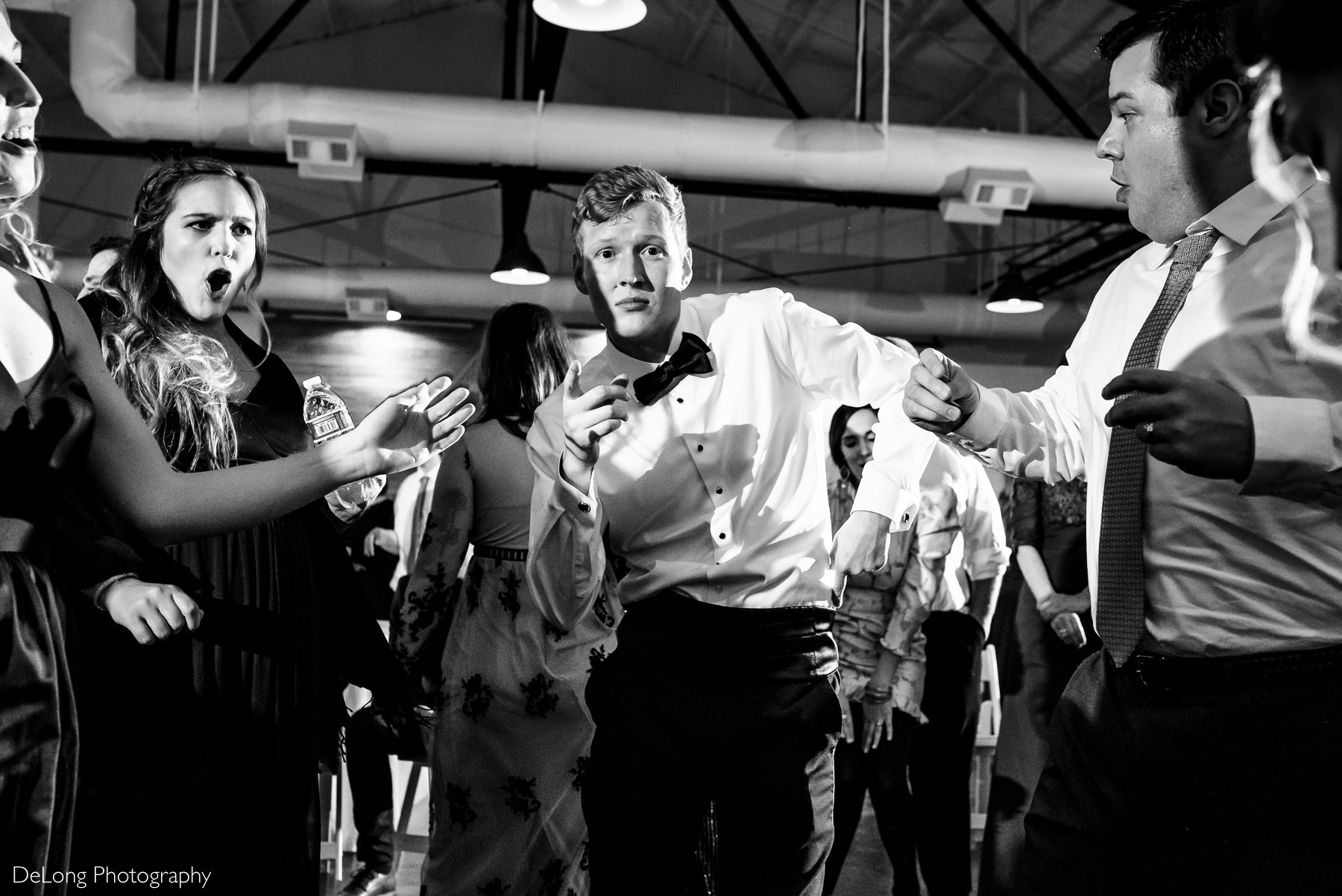 Black and white image of the groom having fun pointing at the camera dancing during his wedding reception at the Westside warehouse in Atlanta by Charlotte wedding photographers DeLong Photography