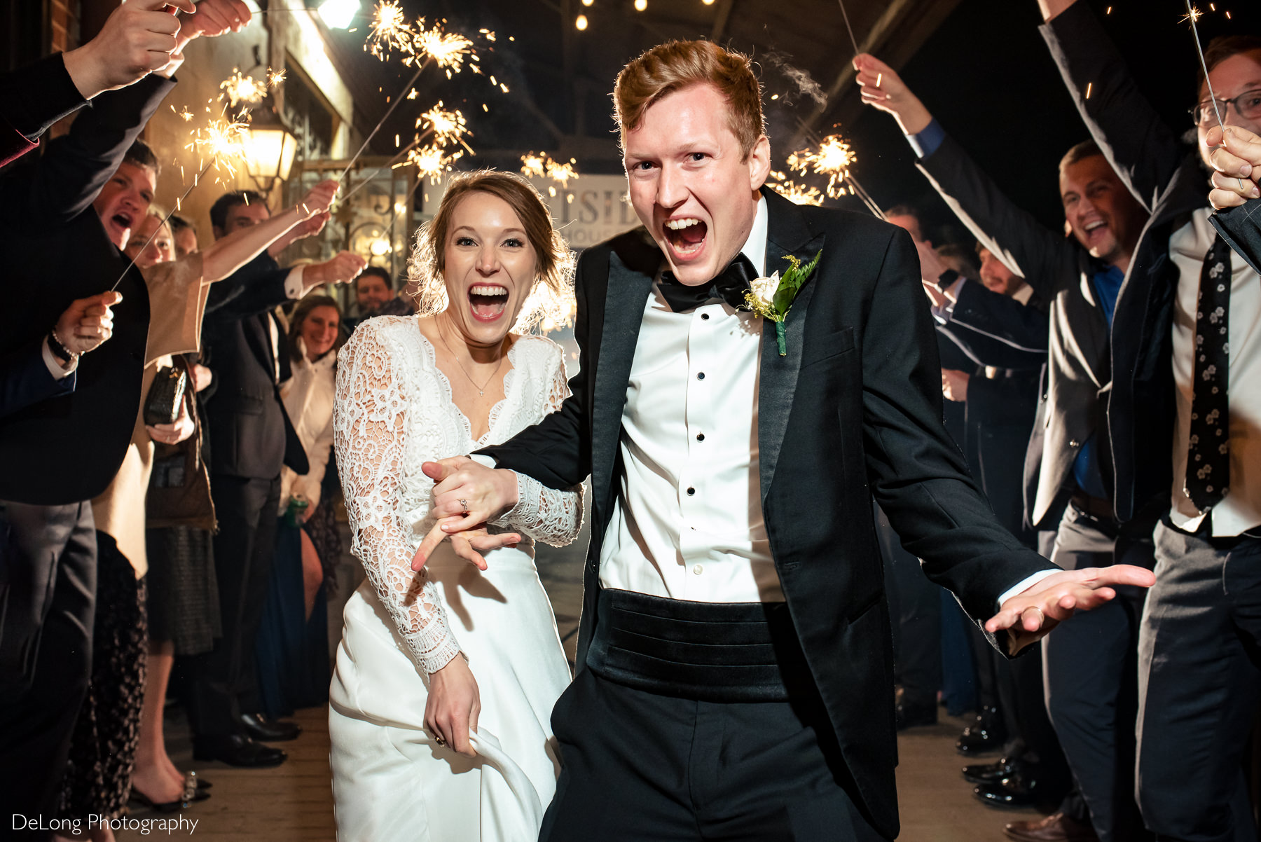 Bride and groom smiling and yelling as they come through the sparklers during their send-off at the Westside warehouse in Atlanta by Charlotte wedding photographers DeLong Photography