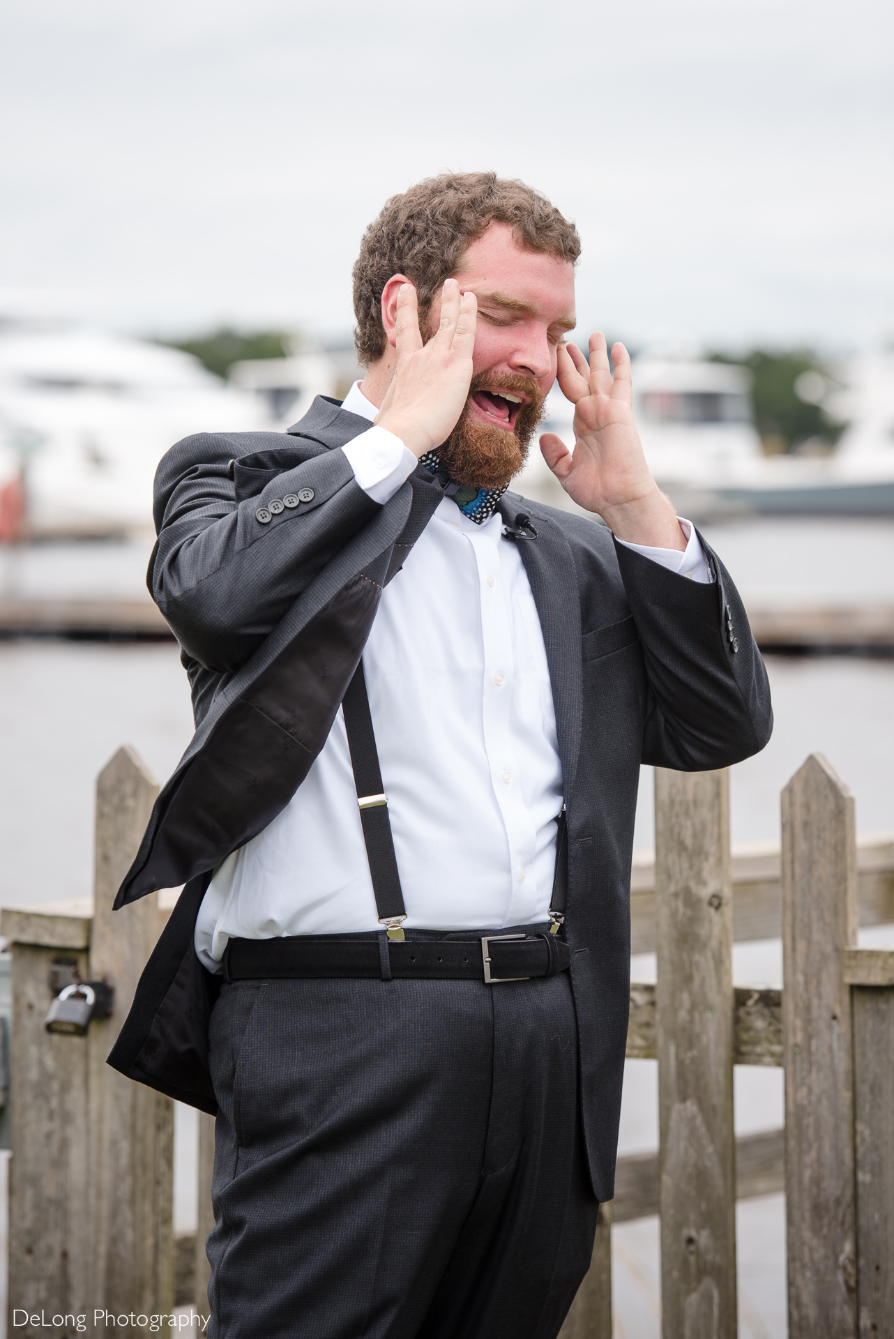 Groom rubbing his eyes reacting to groomsman wearing a dress as a prank during a first look at the Island House by Charlotte Wedding Photographers DeLong Photography