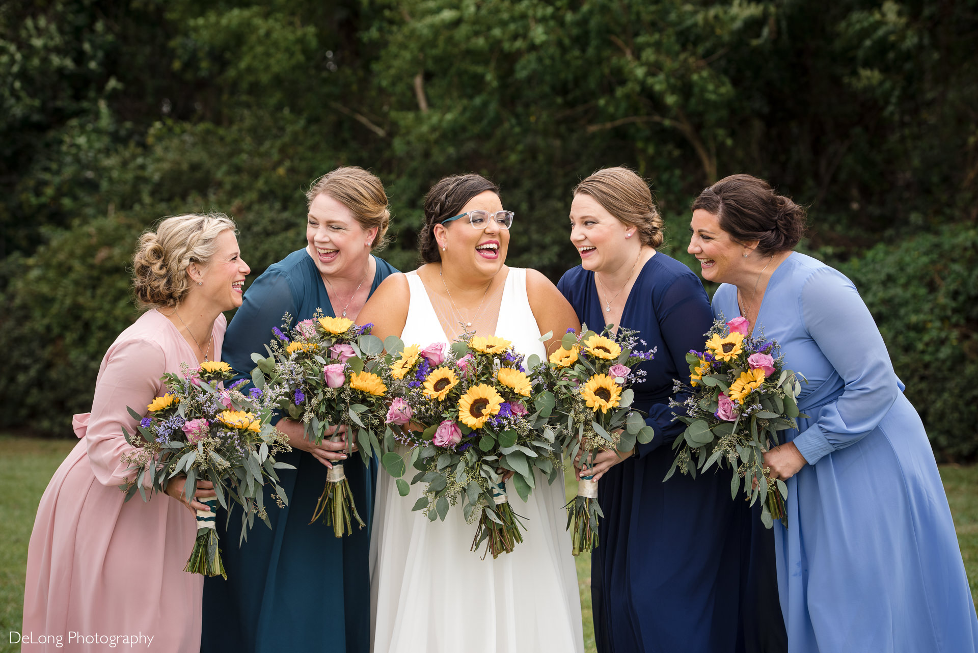 Bride laughing with her bridesmaids holding colorful bouquets and dresses at the Island House in Charleston, SC by Charlotte Wedding Photographers DeLong Photography