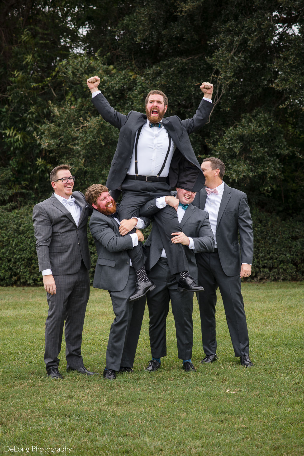 Groom being hoisted up by groomsmen on the lawn at the Island House in Charleston, SC by Charlotte Wedding Photographers DeLong Photography