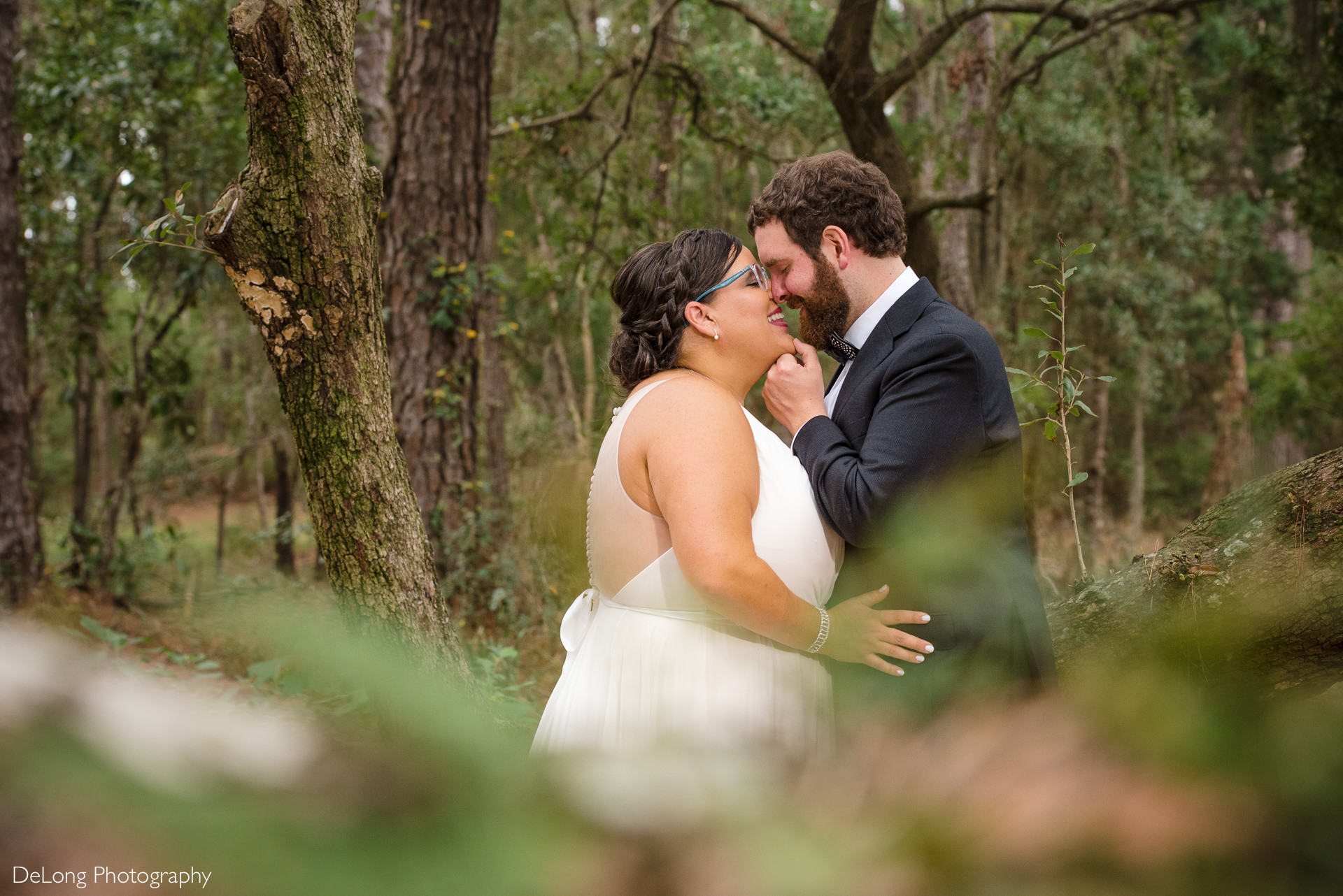 Bride and groom smiling before a kiss at the large oak tree on the property of the Island House in Charleston, SC by Charlotte Wedding Photographers DeLong Photography