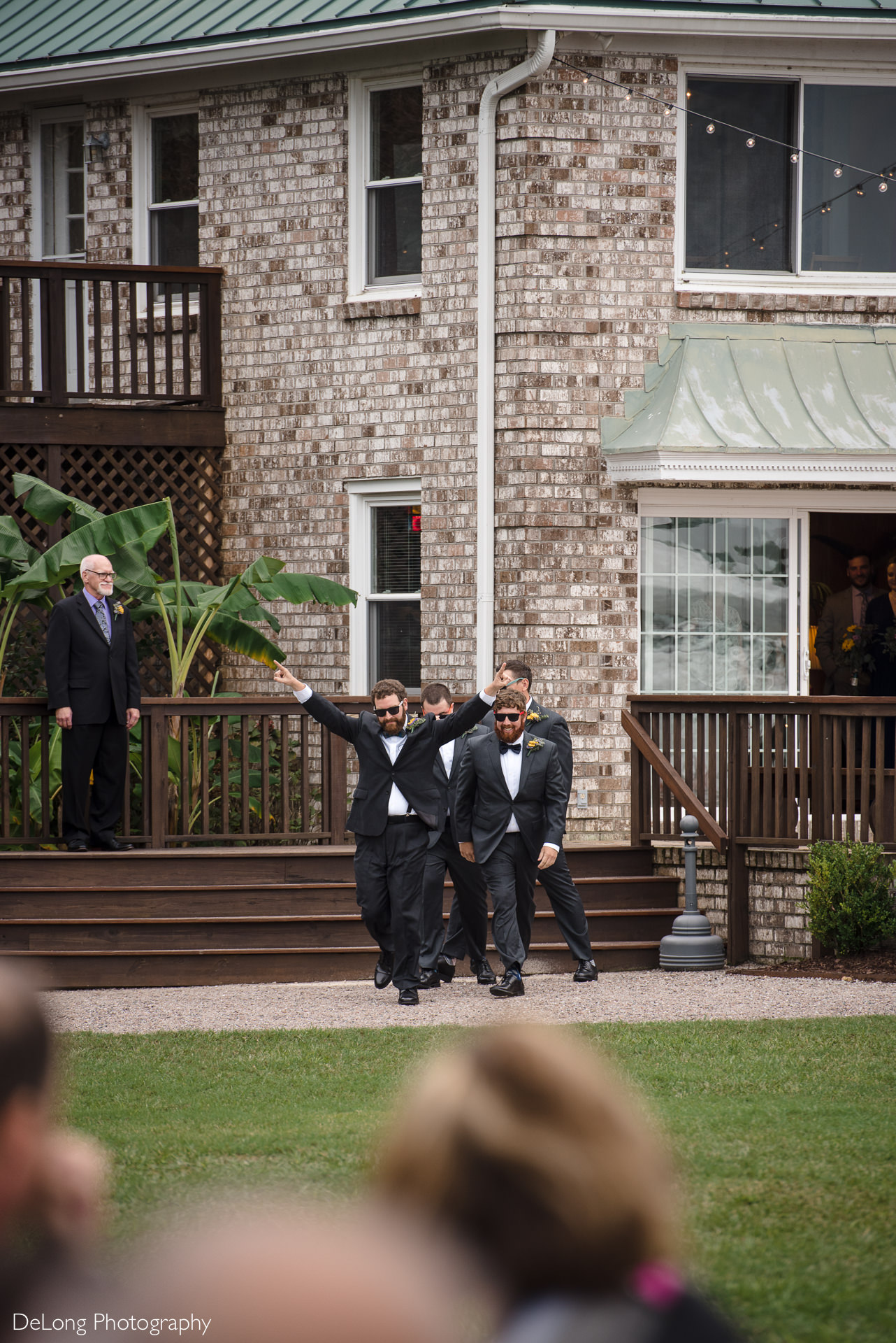 Groom and groomsmen doing a funny ceremony entrance by walking out wearing sunglasses at the Island House in Charleston, SC by Charlotte Wedding Photographers DeLong Photography