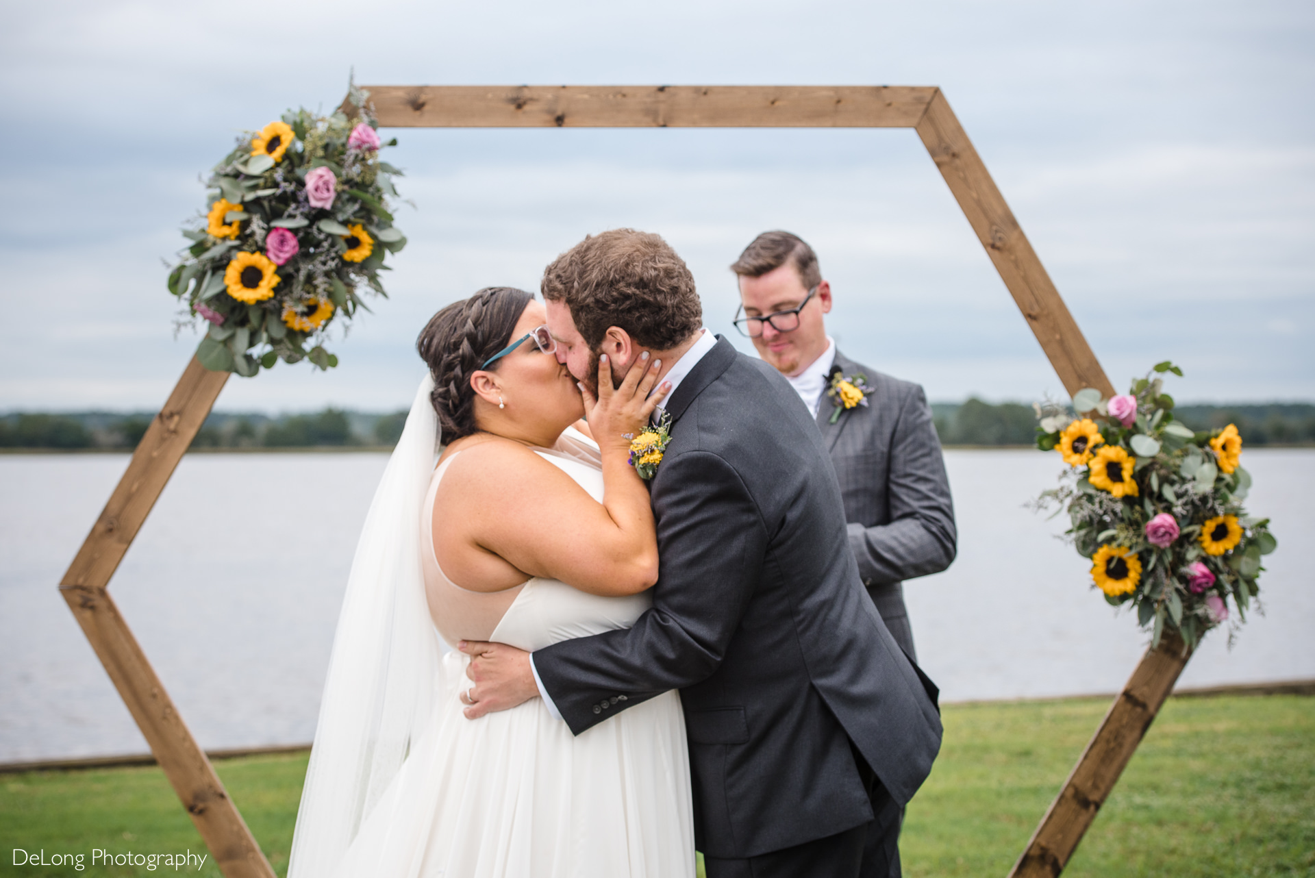 Wedding first kiss with hexagonal arbor adorned with sunflowers at the Island House in Charleston, SC by Charlotte Wedding Photographers DeLong Photography