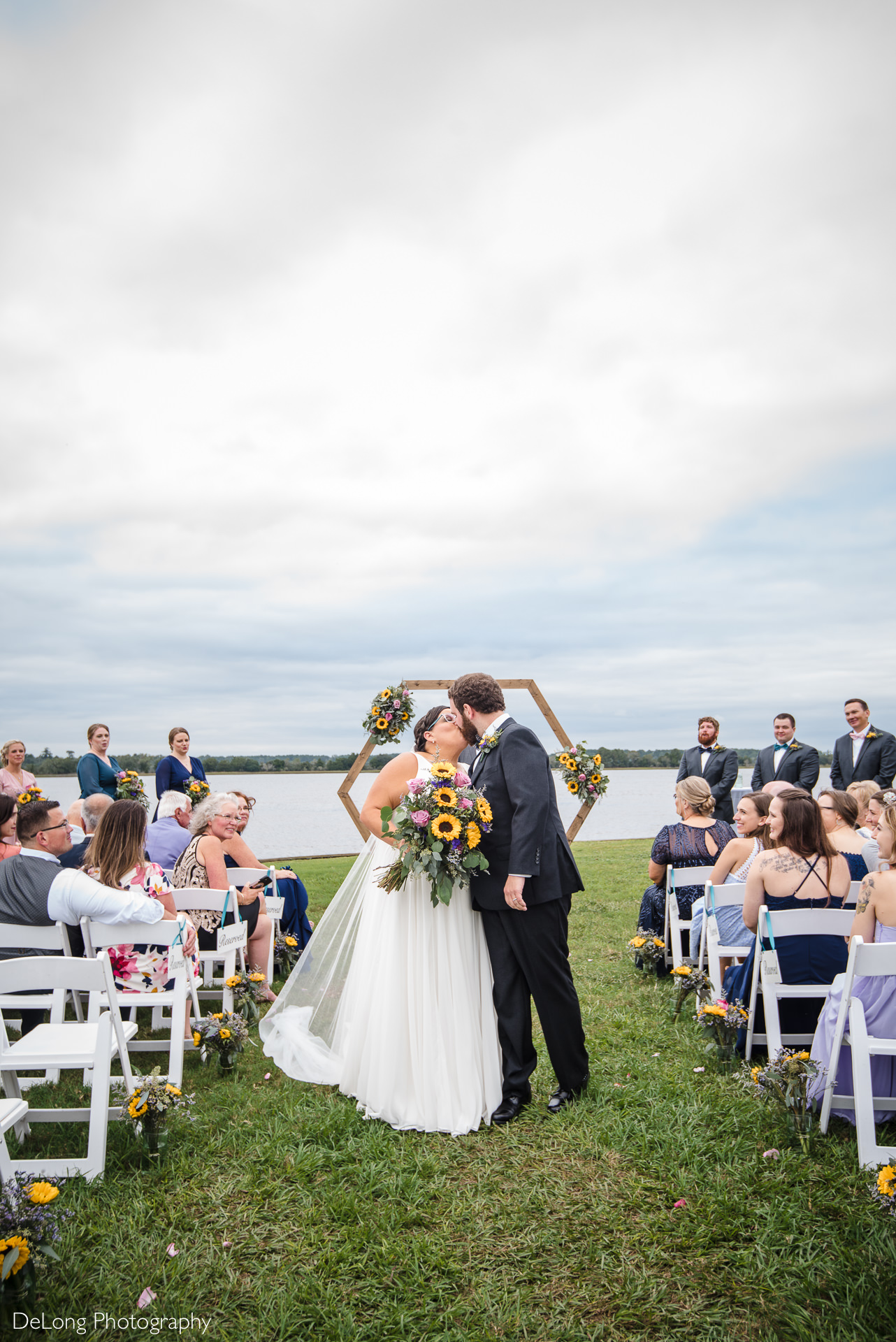 Bride and groom share a kiss partway down the aisle during the recessional at the Island House in Charleston, SC by Charlotte Wedding Photographers DeLong Photography