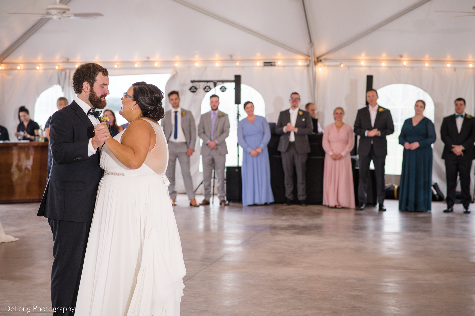 Bride and groom sharing their first dance with their wedding party in the background at the Island House in Charleston, SC by Charlotte Wedding Photographers DeLong Photography