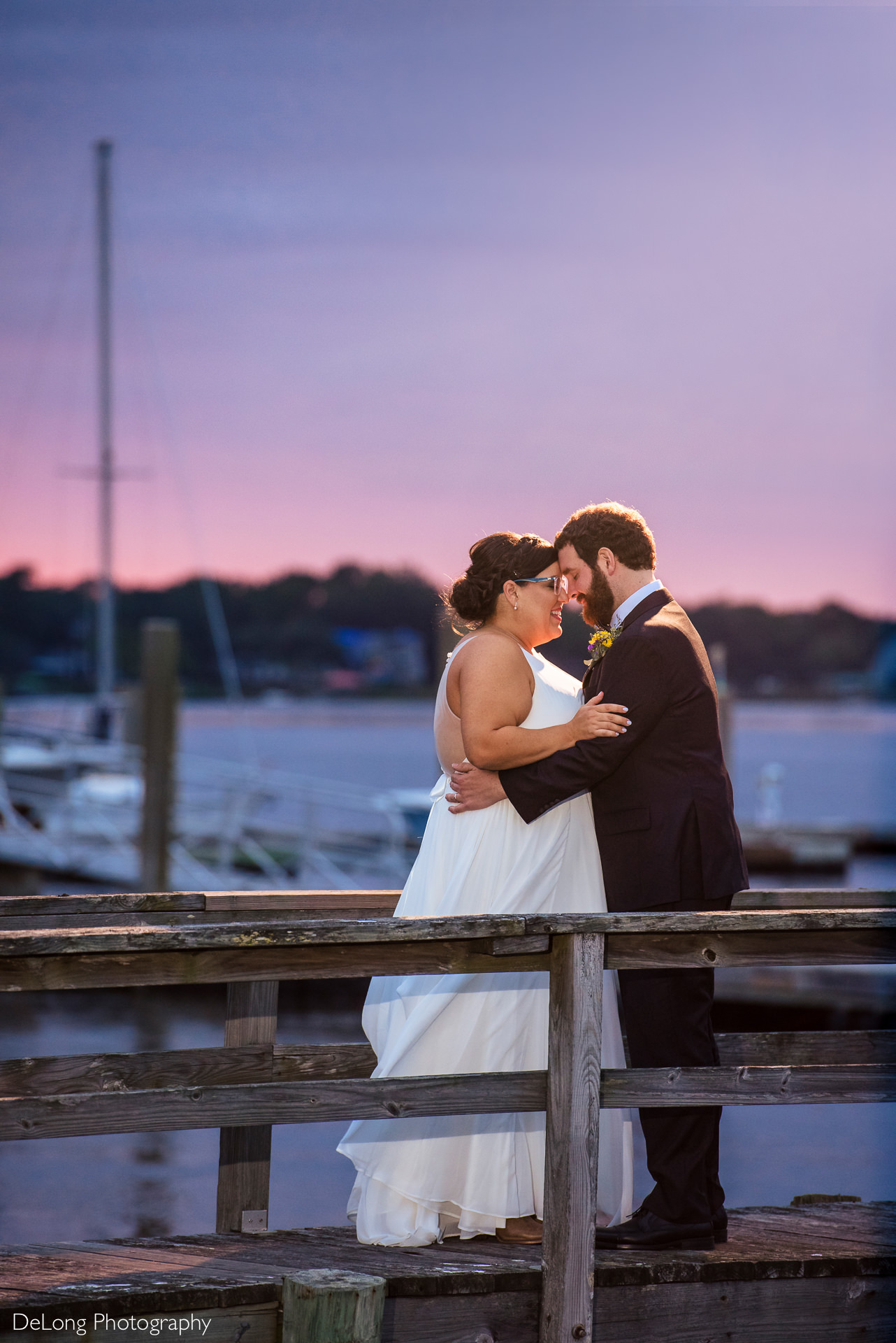 Portrait of bride and groom with their foreheads together during a purple and pink sunset at the Island House in Charleston, SC by Charlotte Wedding Photographers DeLong Photography