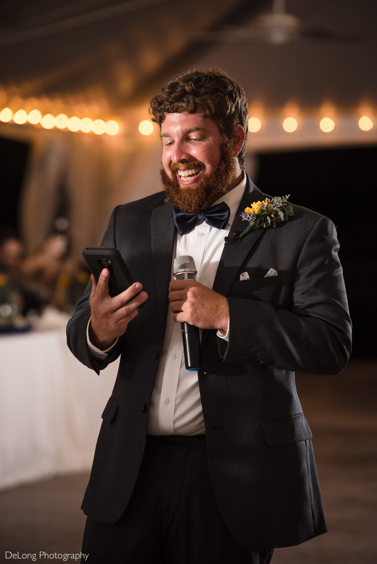 Brother of the groom holding his cell phone laughing while reading his wedding toast at the Island House in Charleston, SC by Charlotte Wedding Photographers DeLong Photography