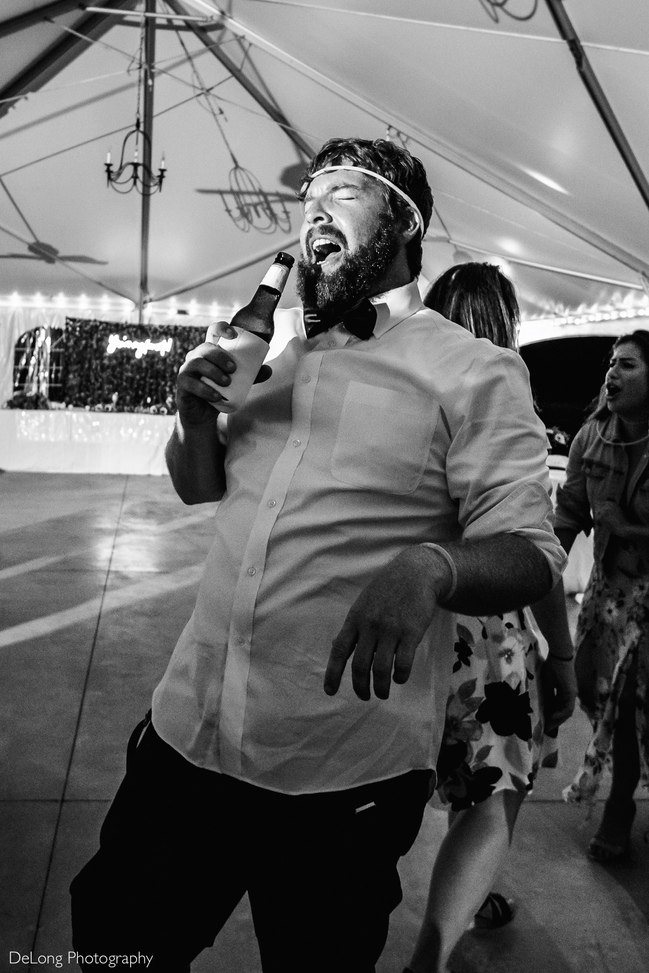 Groomsman singing words to a song into a bottle of beer on the dance floor at a wedding reception at the Island House in Charleston, SC by Charlotte Wedding Photographers DeLong Photography