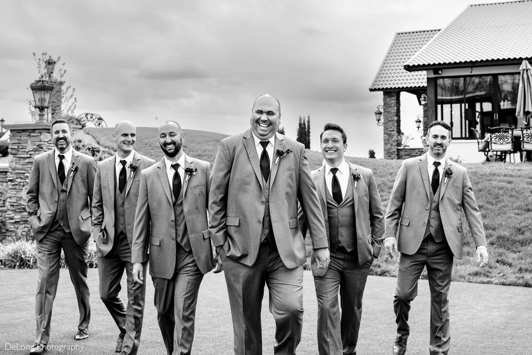 Black an white image of groom and groomsmen laughing and walking toward the camera at Childress Vineyards by Charlotte Wedding Photographers DeLong Photography